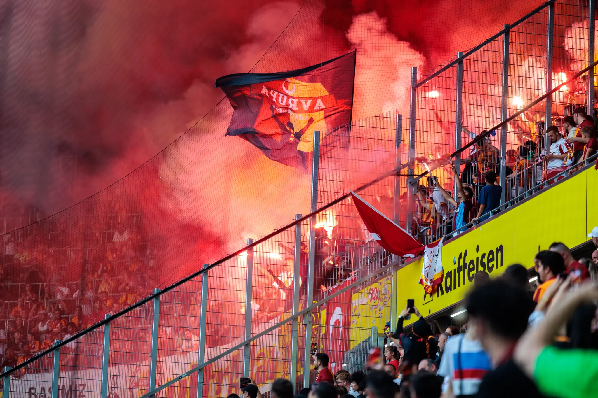 Feiernde Fußballfans von Galatasaray Istanbul tauchen die Raiffeisen Arena in roten Rauch 