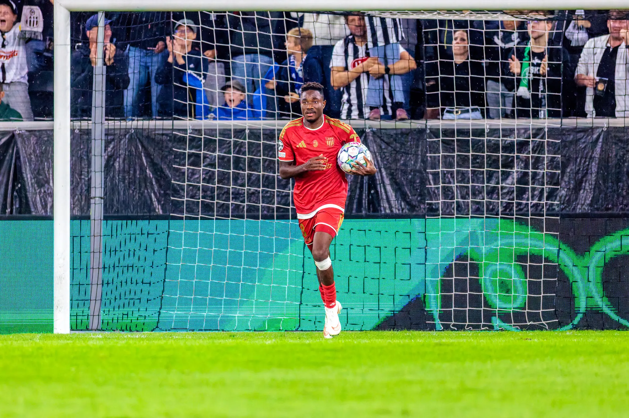 LASK-Torschütze Moses Usor (8) trägt nach seinem Ausgleich den Ball hinter dem Tor zurück ins Spiel.