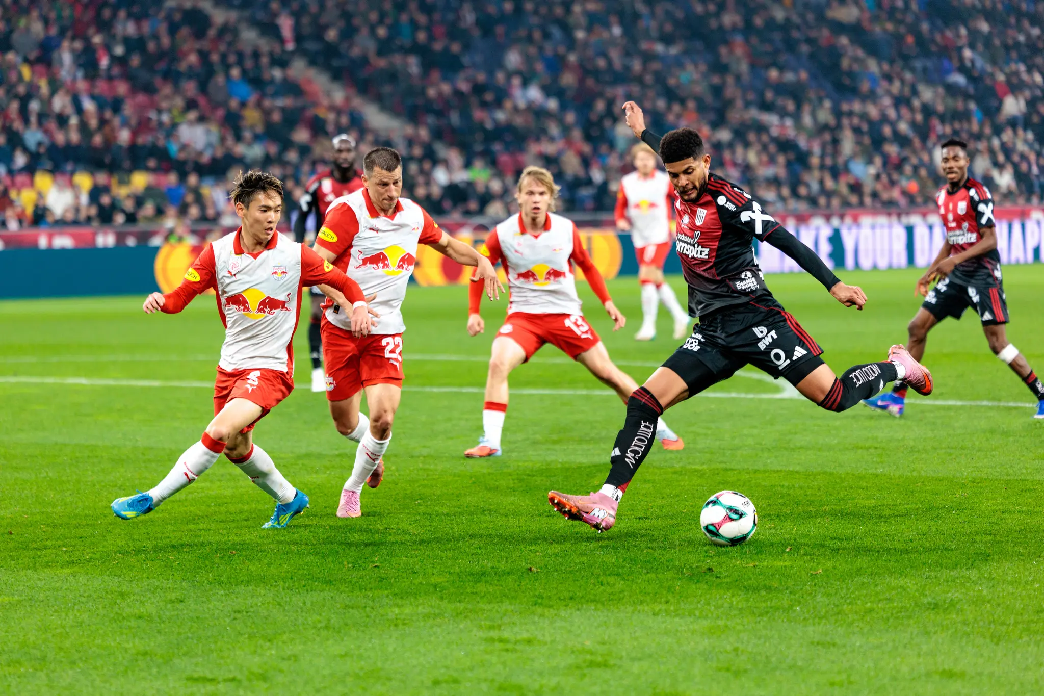 Ein Spieler des LASK zieht im Duell der ADMIRAL Bundesliga gegen Red Bull Salzburg kraftvoll zum Torschuss ab, während die Salzburger Abwehrspieler den Angriff zu unterbinden versuchen