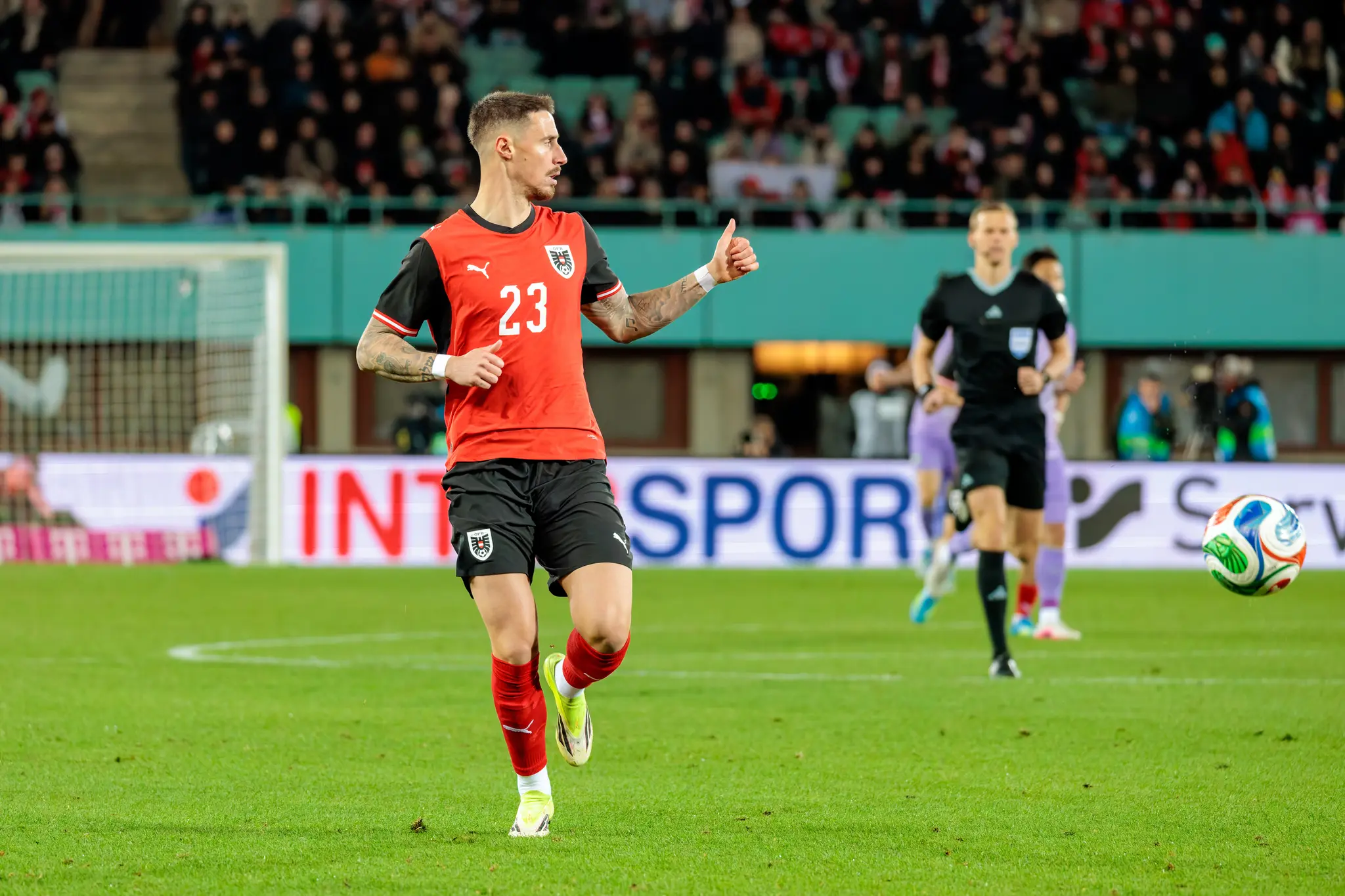 Ein Spieler der österreichischen Fußballnationalmannschaft im roten Trikot mit der Nummer 23 zeigt während eines Spiels einen Daumen nach oben
