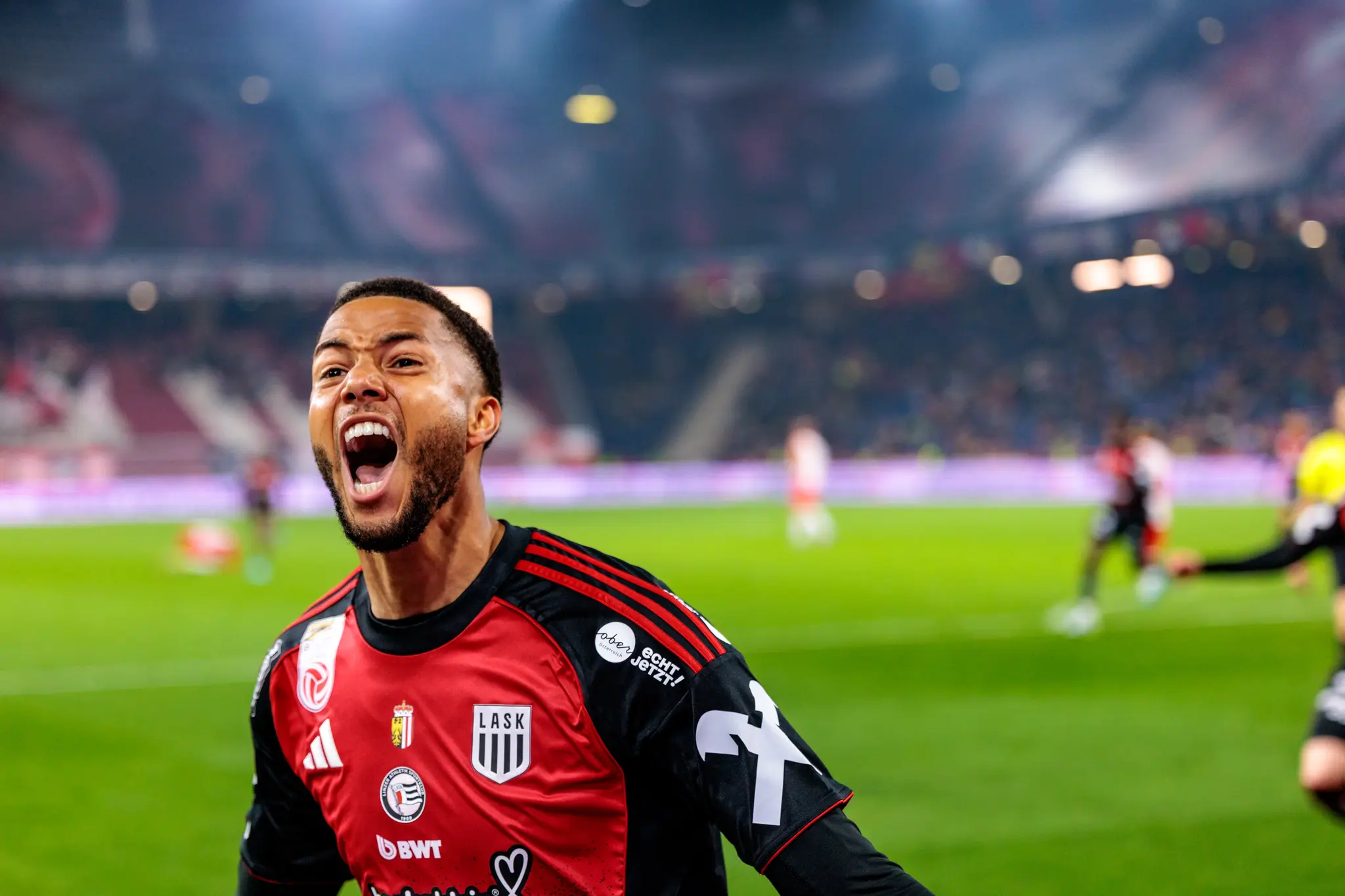 Ein LASK-Fußballspieler im roten Trikot jubelt mit einem emotionalen Schrei nach einem entscheidenden Treffer im Spiel