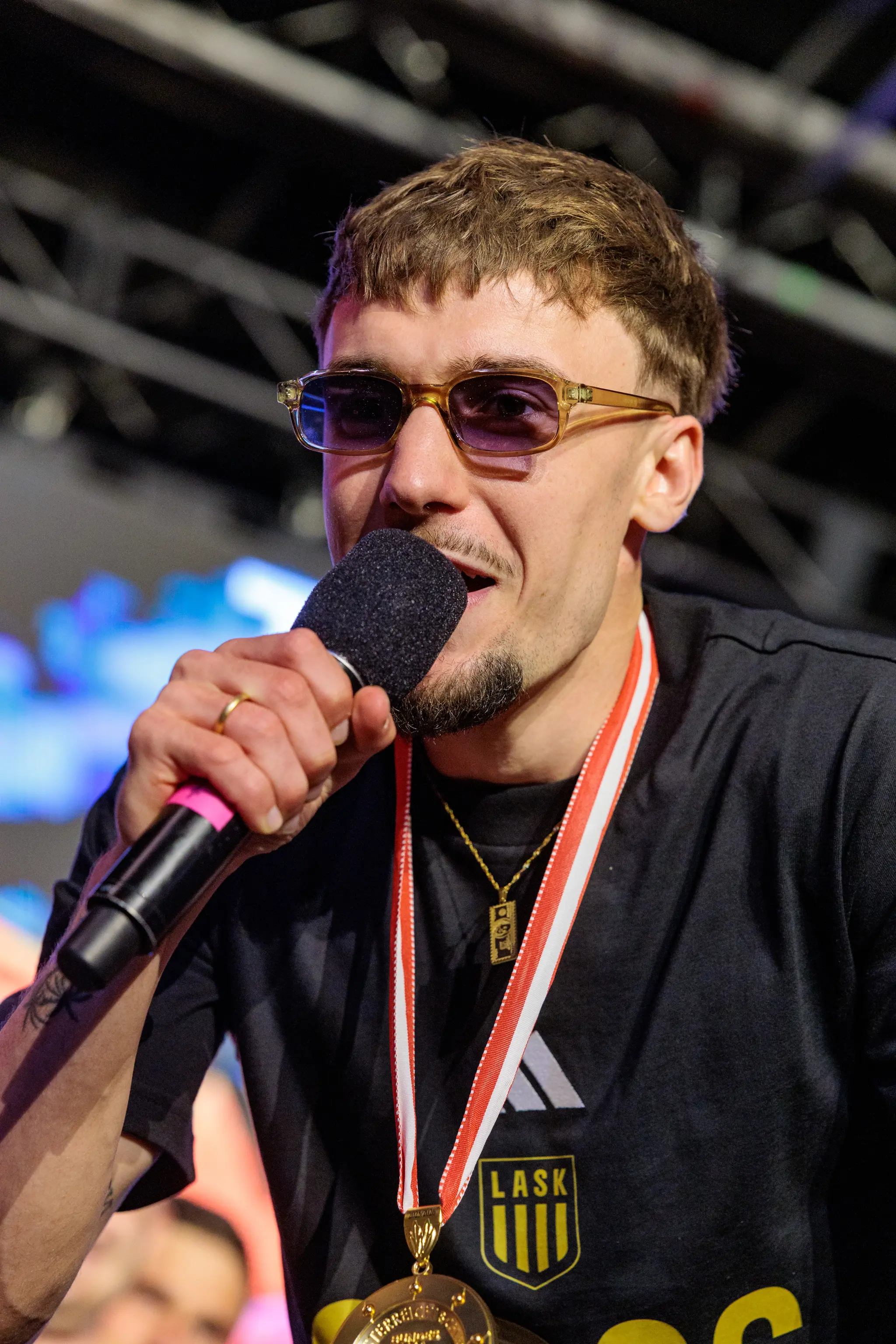Ein Spieler des LASK trägt eine Sonnenbrille und spricht während der Meisterfeier mit einem Mikrofon
