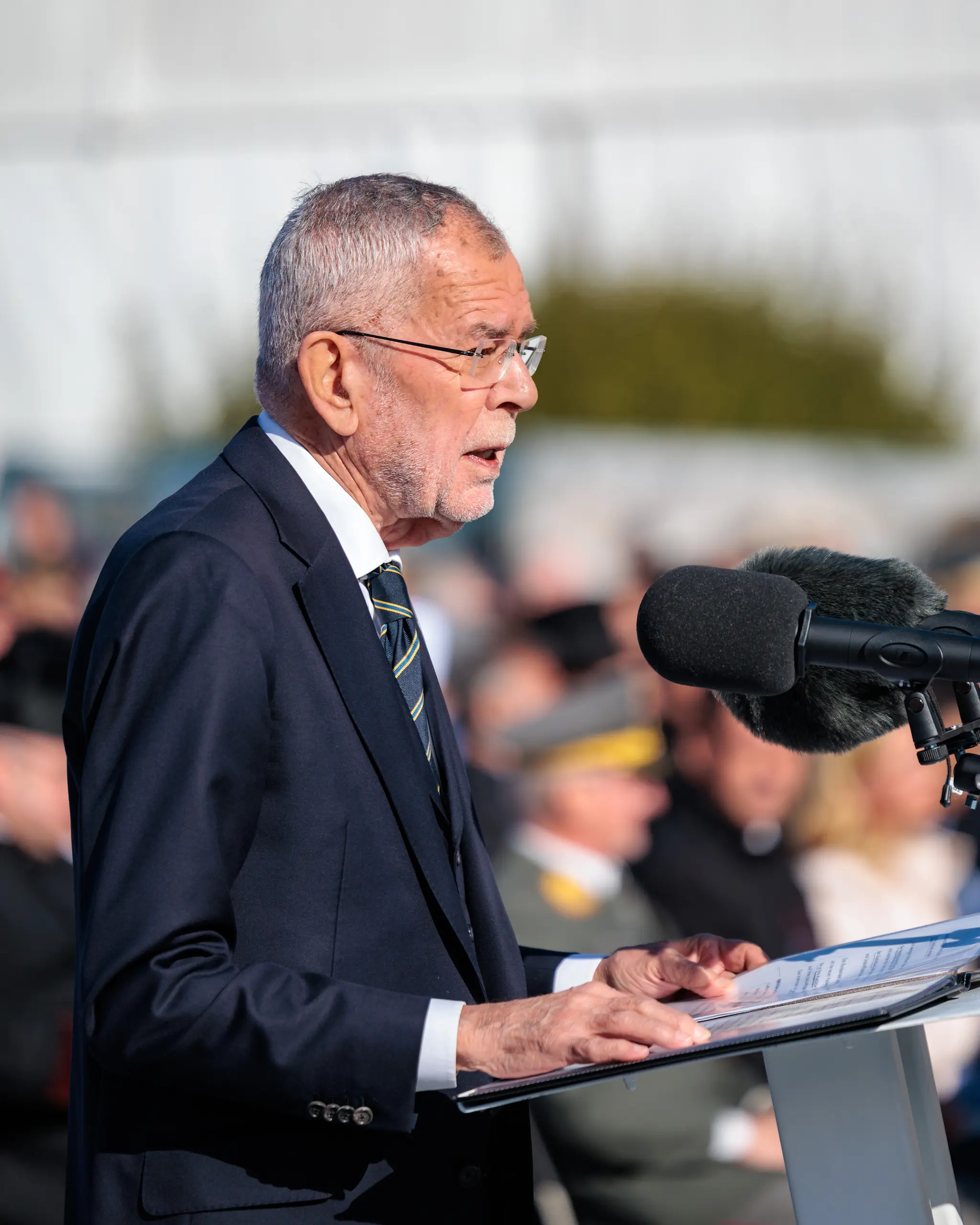 Bundespräsident Alexander Van der Bellen spricht mit Brille und dunklem Anzug am Rednerpult bei der Angelobung am Heldenplatz.