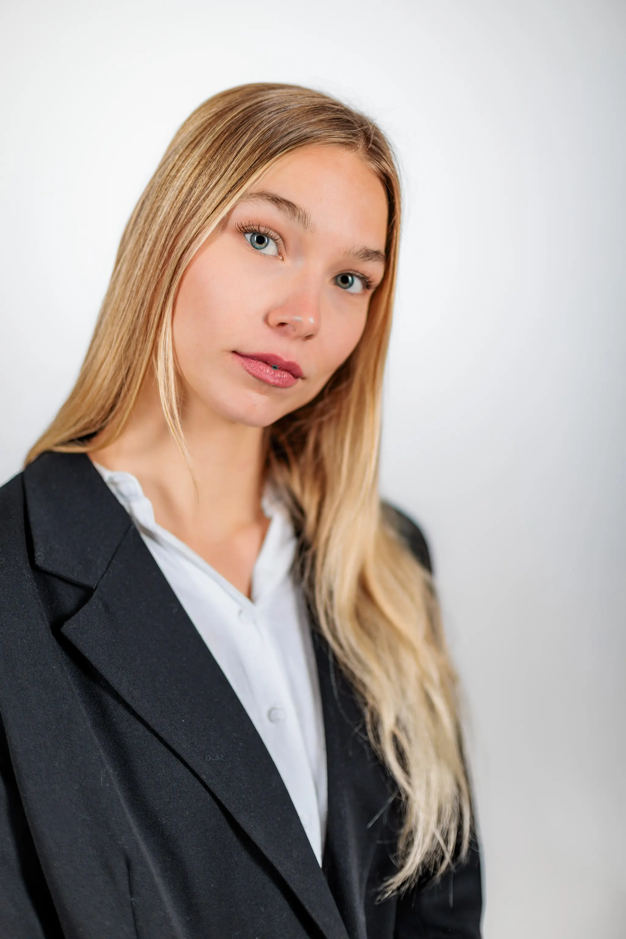 Professionelles Business-Headshot von Model Kathrin mit langen blonden Haaren im schwarzen Blazer vor einem neutralen Studio-Hintergrund