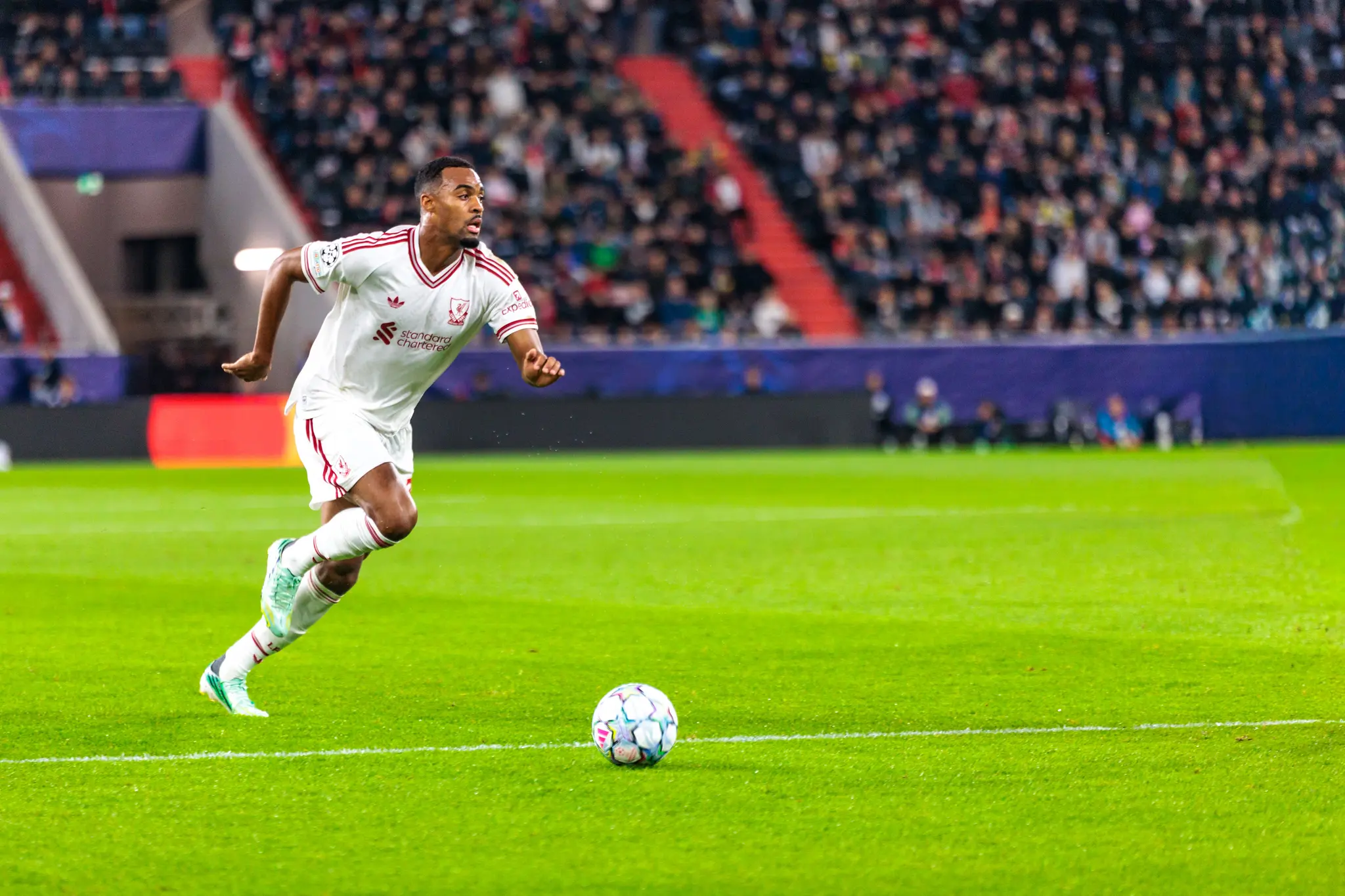 Ein Liverpooler Spieler sprintet mit dem Ball über den Rasen, im Hintergrund sind die vollbesetzten Ränge zu sehen.