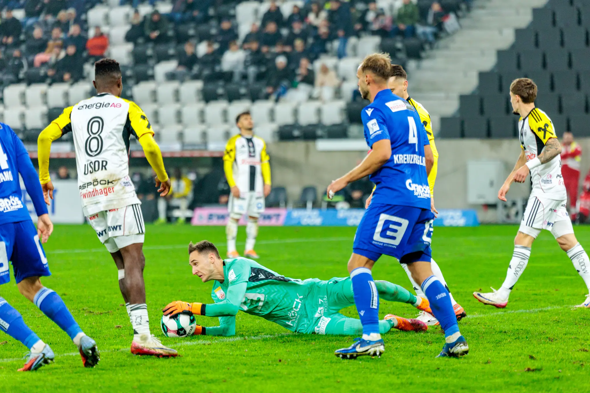 GAK-Goalie Jakob Meierhofer pariert den Ball am Boden liegend im Duell mit LASK-Stürmer Moses Usor
