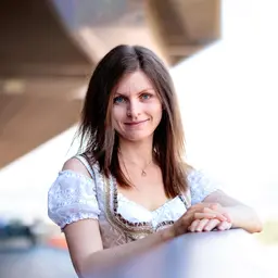Eine lächelnde Frau im traditionellen Dirndl mit blauer Bluse und aufwendiger Stickerei blickt freundlich in die Kamera lens: 56mm F1.4 DC DN | Contemporary 018