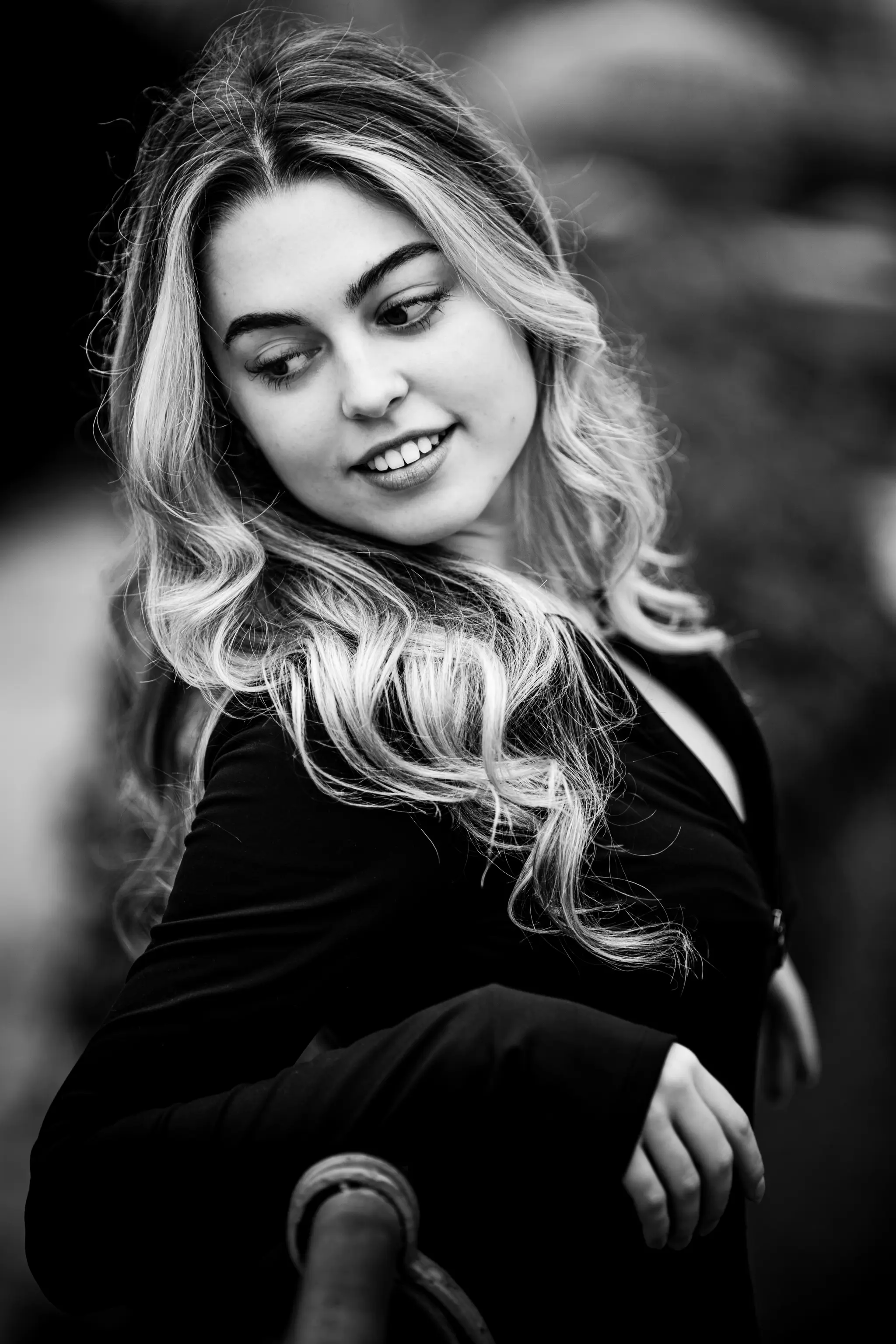Stimmungsvolles Schwarz-Weiß-Porträt von Model Valentina mit langen blonden Locken, die mit einem leichten Lächeln nach unten zur Seite blickt