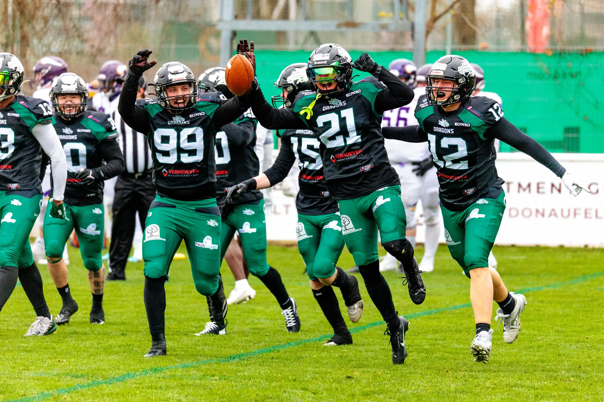 Jubelnde American Football Spieler der Danube Dragons feiern ausgelassen einen Touchdown mit erhobenen Armen und dem Football