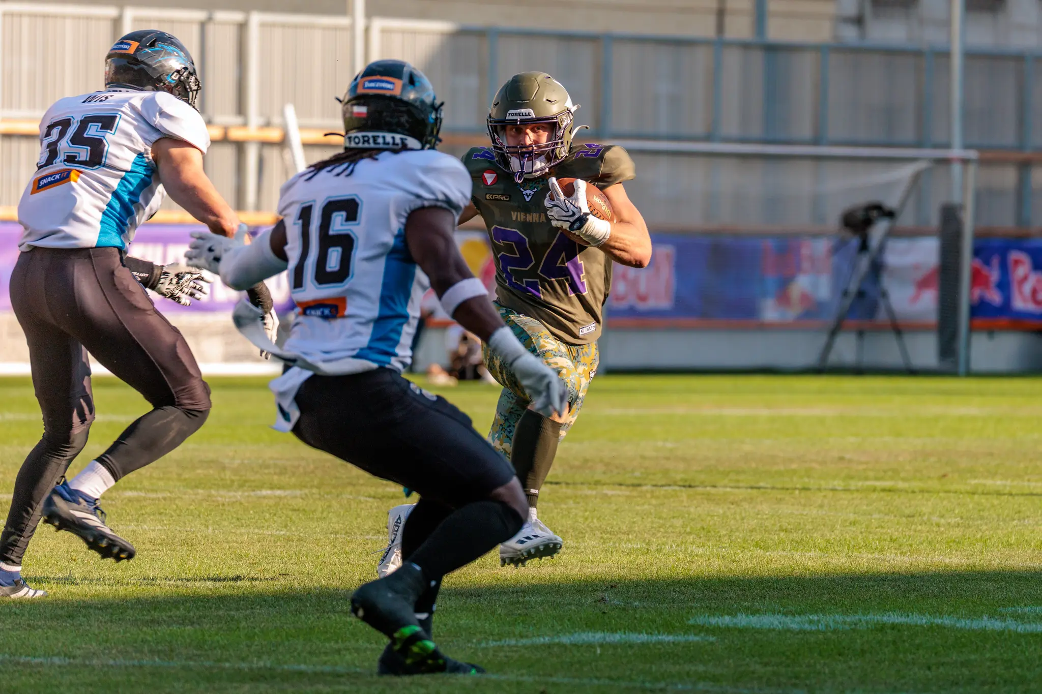Vikings-Spieler Karri Pajarinen (Nummer 24) läuft mit dem Ball, während die Panthers-Spieler 35 und 16 den Laufweg schließen.