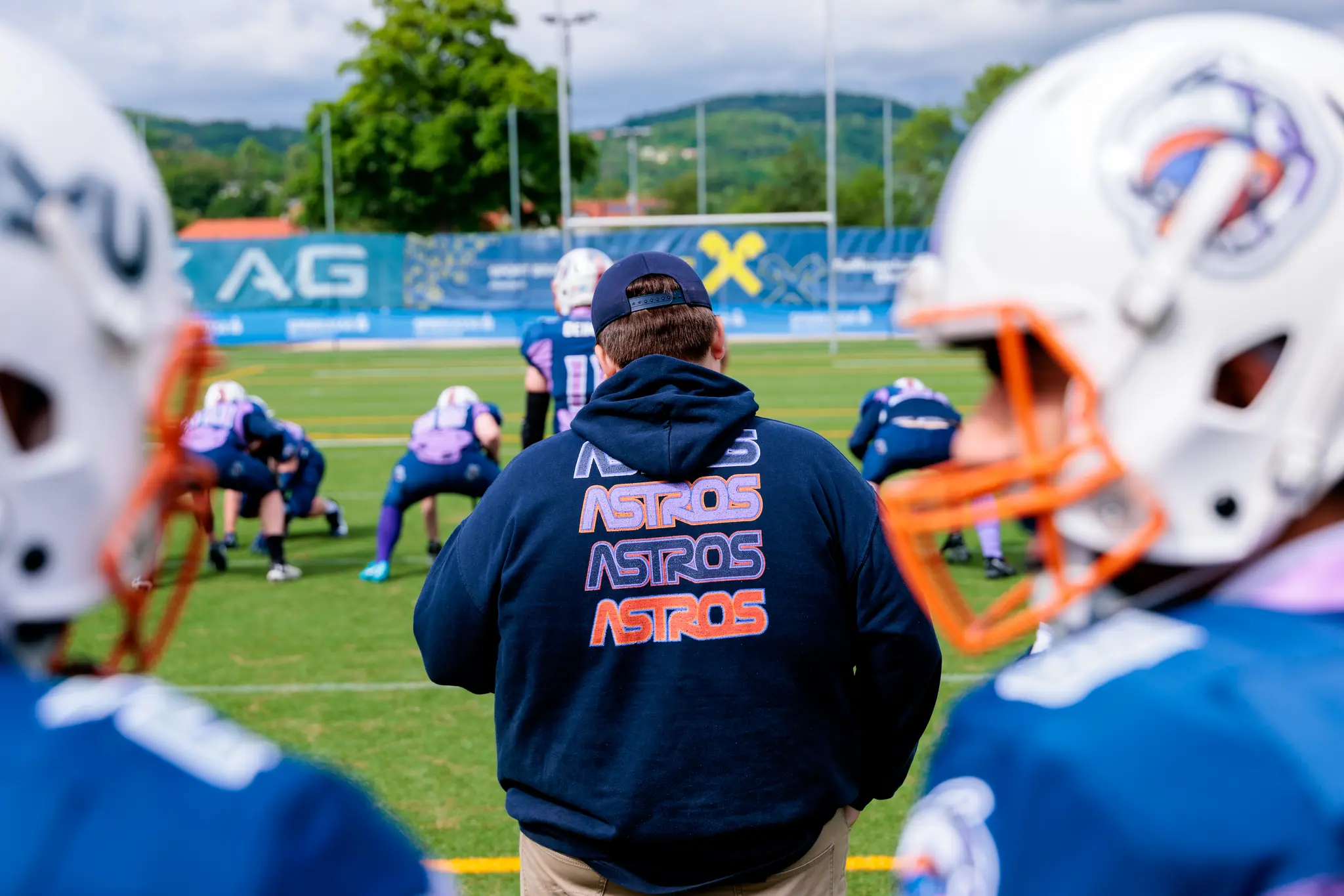 Ein American Football Trainer der Astros schaut seinen Spielern beim Training auf dem Feld zu 
