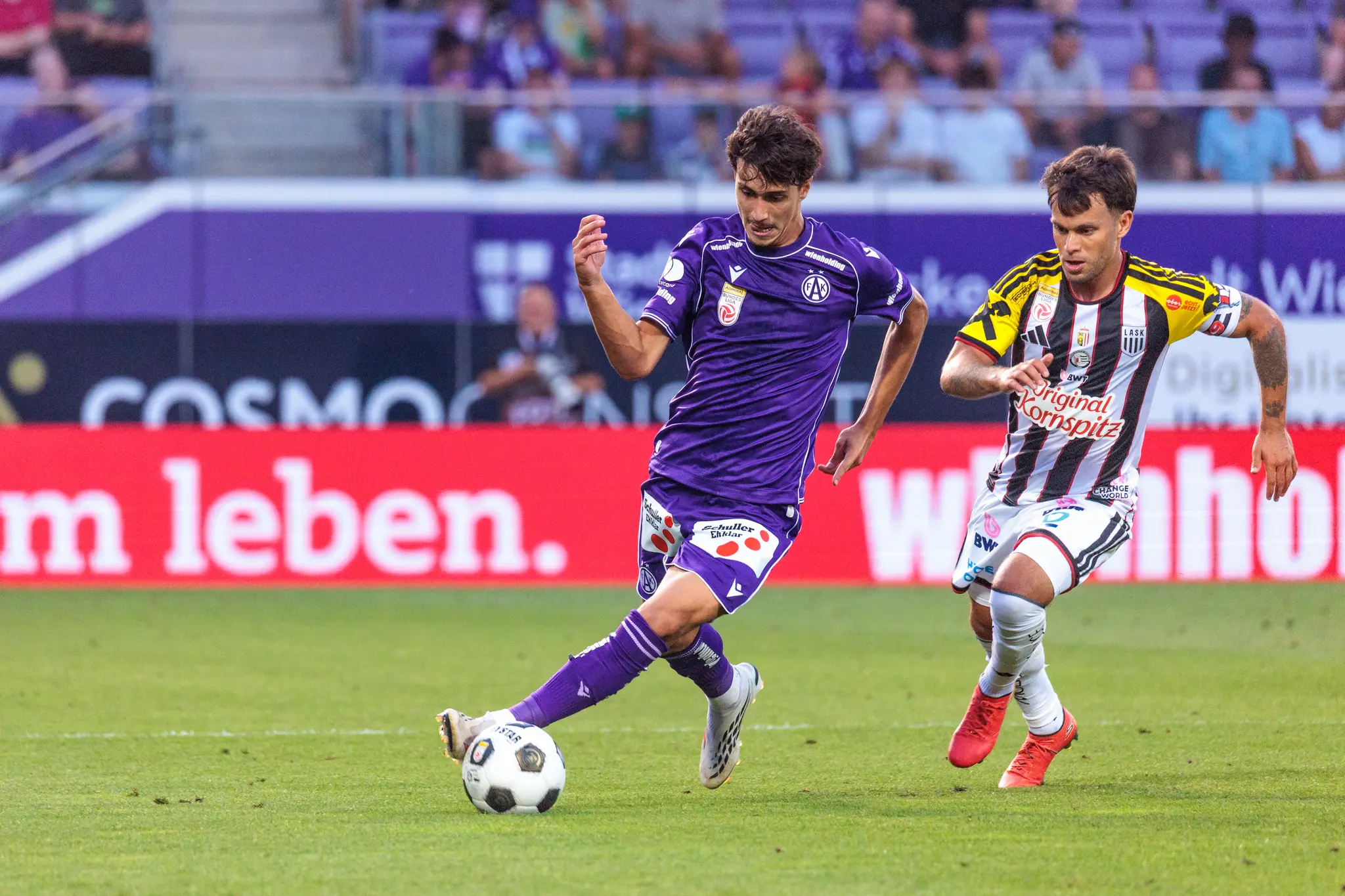 Austria-Spieler dribbelt in der Nachspielzeit der ersten Halbzeit, LASK-Kapitän Horvath verfolgt ihn