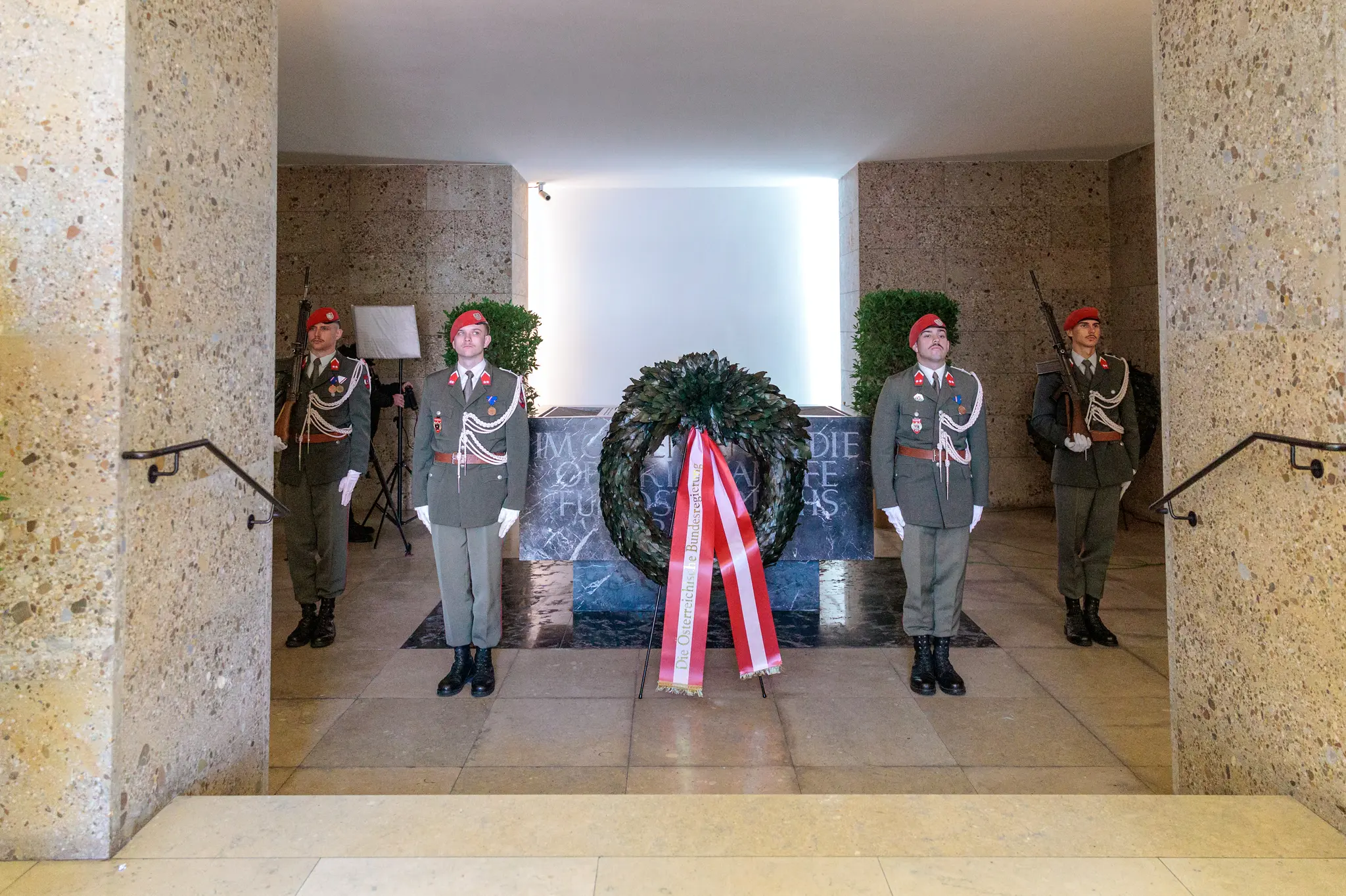 Ein Kranz mit rot-weiß-roter Schleife steht vor der Gedenktafel im Weiheraum des Äußeren Burgtors, vier Gardesoldaten halten Wache.