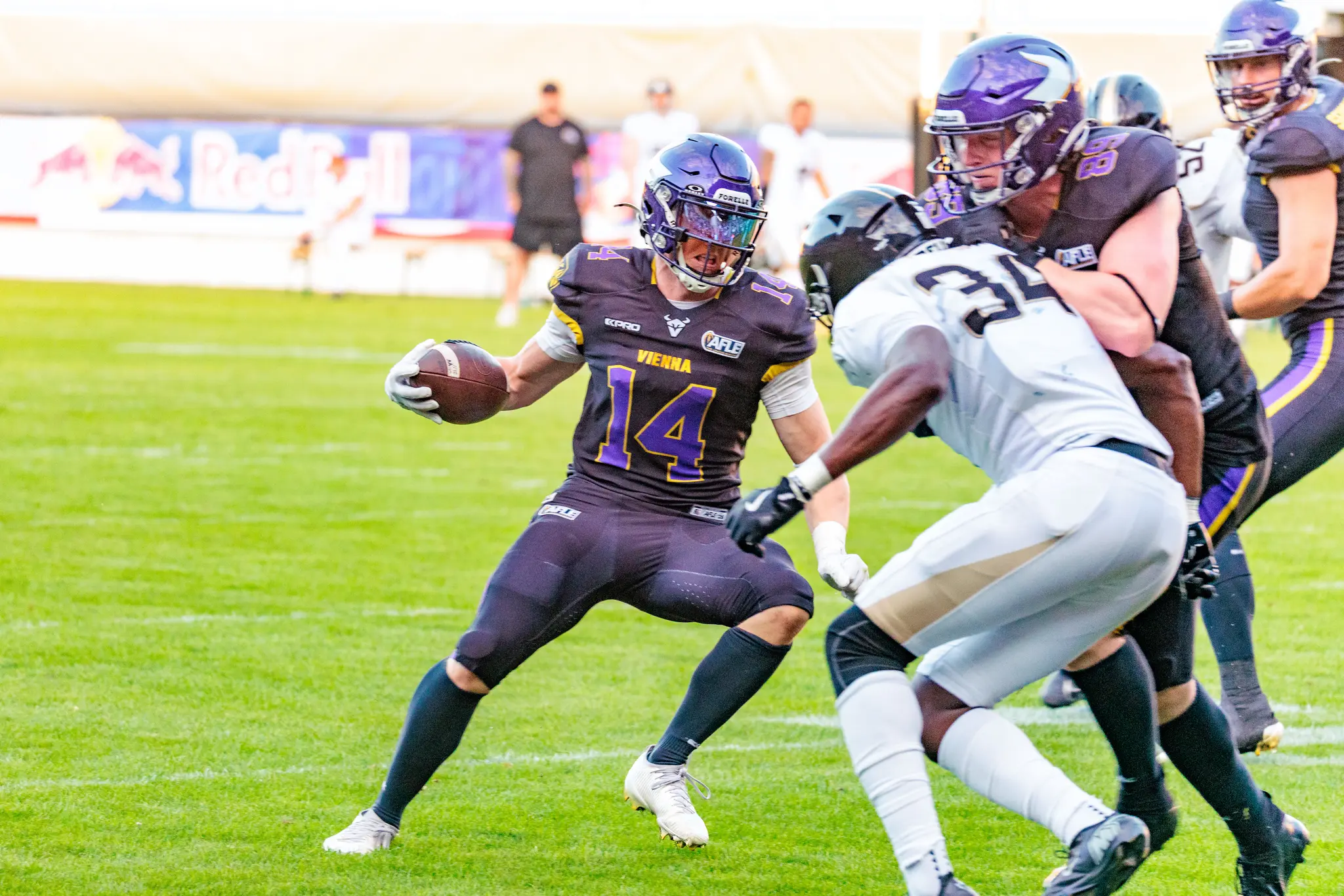 Yannick Mayr (14) zieht mit dem Ball an einem London-Verteidiger (34) vorbei, während seine Offensive Line Blocker stellt – Catch-and-Run kurz vor der Halbzeit.
