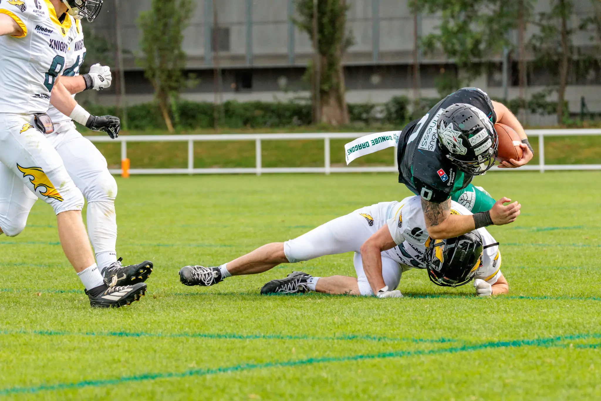Ein Spieler der Danube Dragons wird von einem Vienna Knights Verteidiger am Boden getackelt während eines intensiven American Football Spiels in der Austrian Football League
