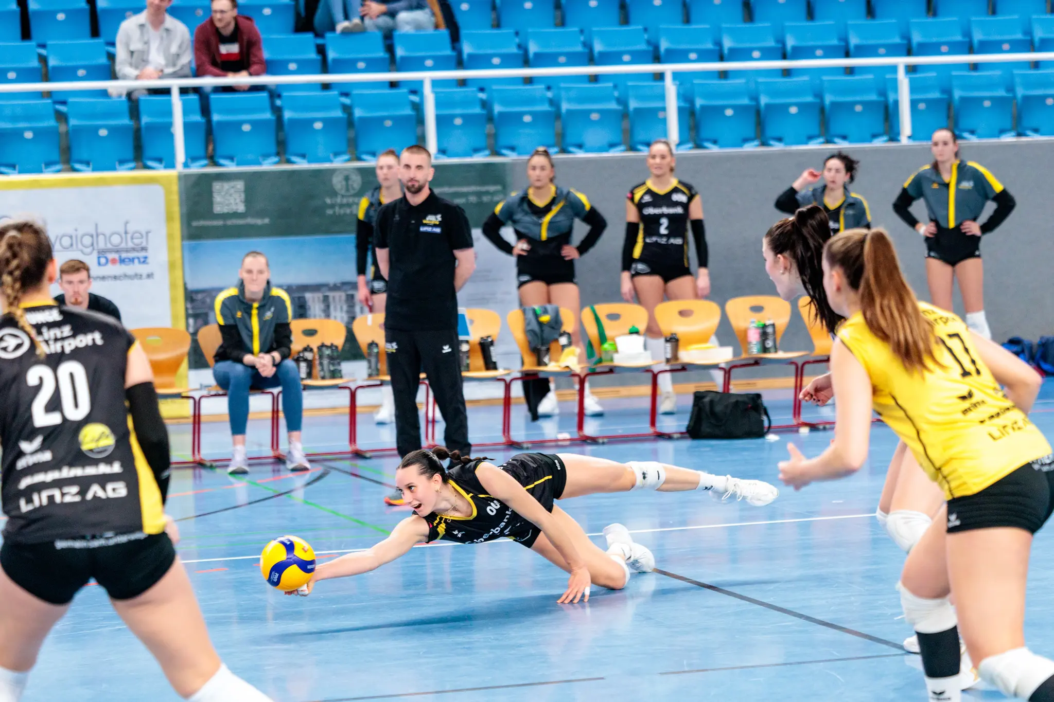 Volleyballerin in Schwarz-Gelb hechtet nach dem Ball auf dem Spielfeld