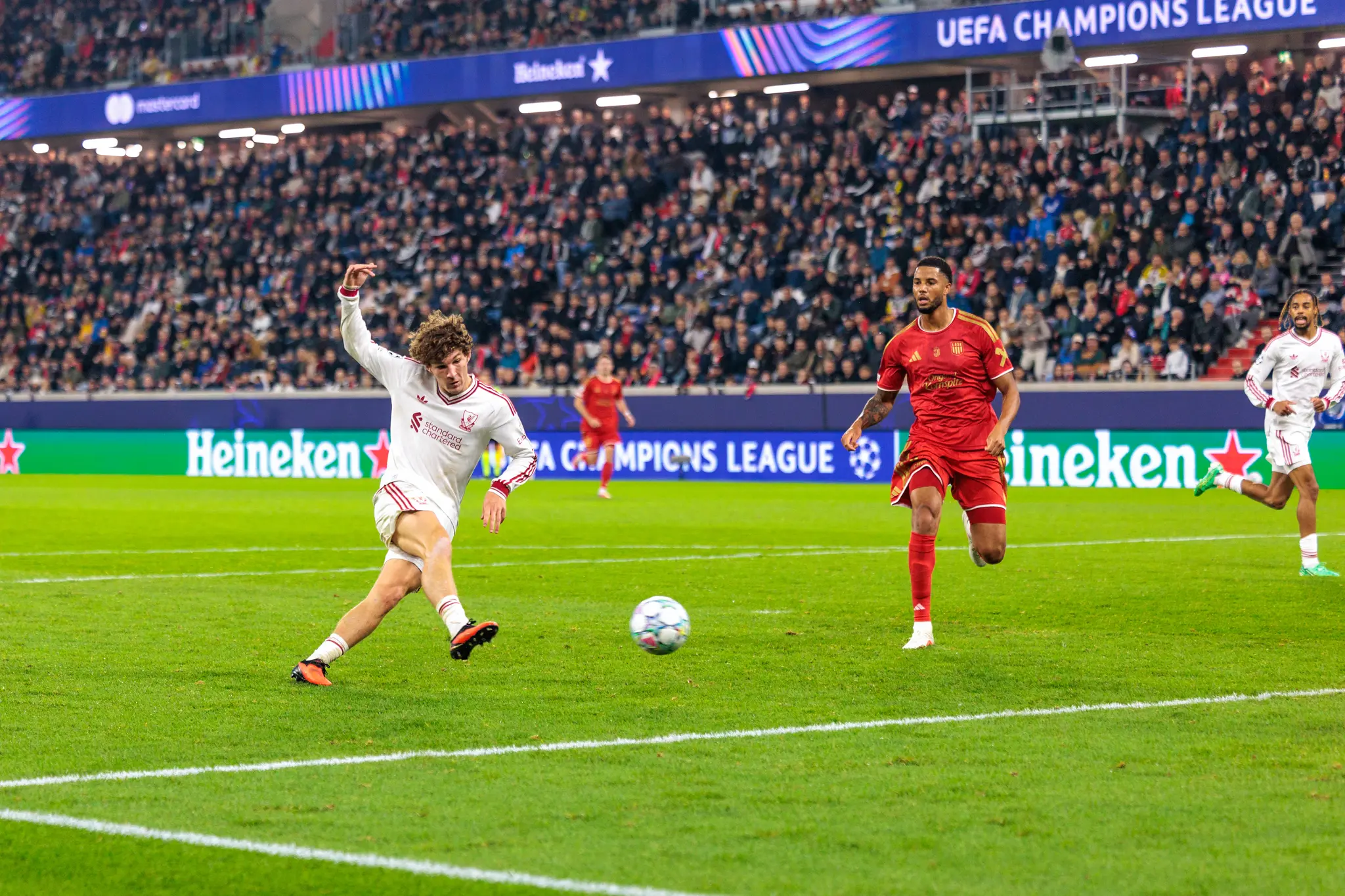 Ein Liverpooler Spieler schießt den Ball in die Luft, ein LASK-Spieler sprintet daneben her.
