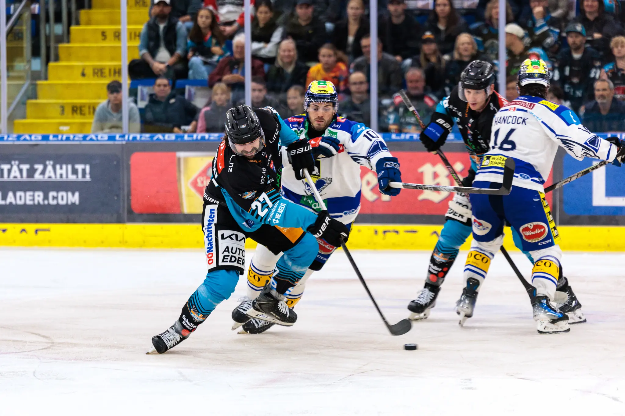 Eishockeyspieler Shawn St-Amant der Steinbach Black Wings Linz in dynamischer Puckführung gegen Kevin Hancock des EC VSV auf dem Eis