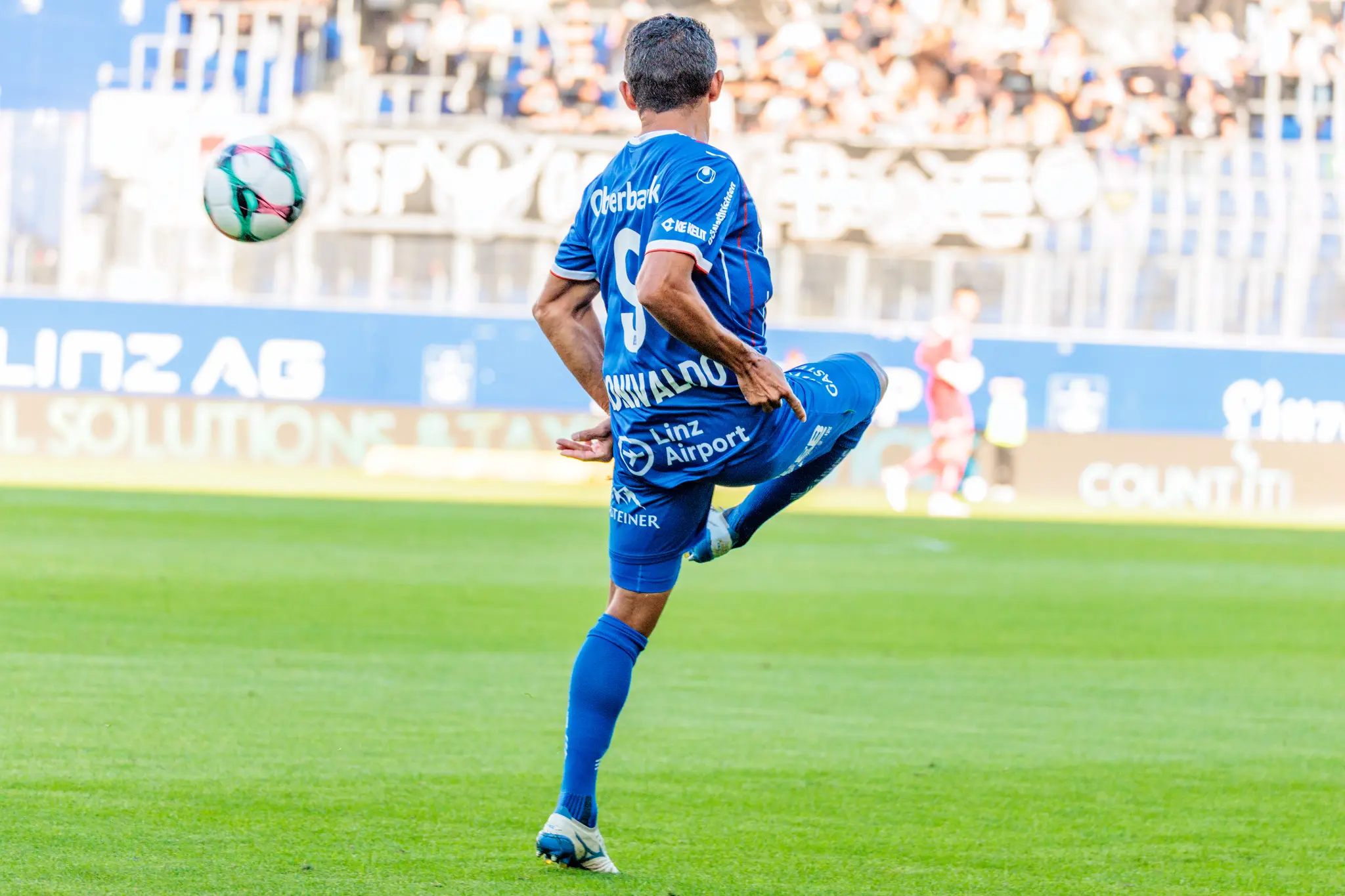 Rückansicht des Stürmers Ronivaldo vom FC Blau-Weiß Linz mit der Nummer 9, der während des Spiels elegant einen Ball in der Luft annimmt