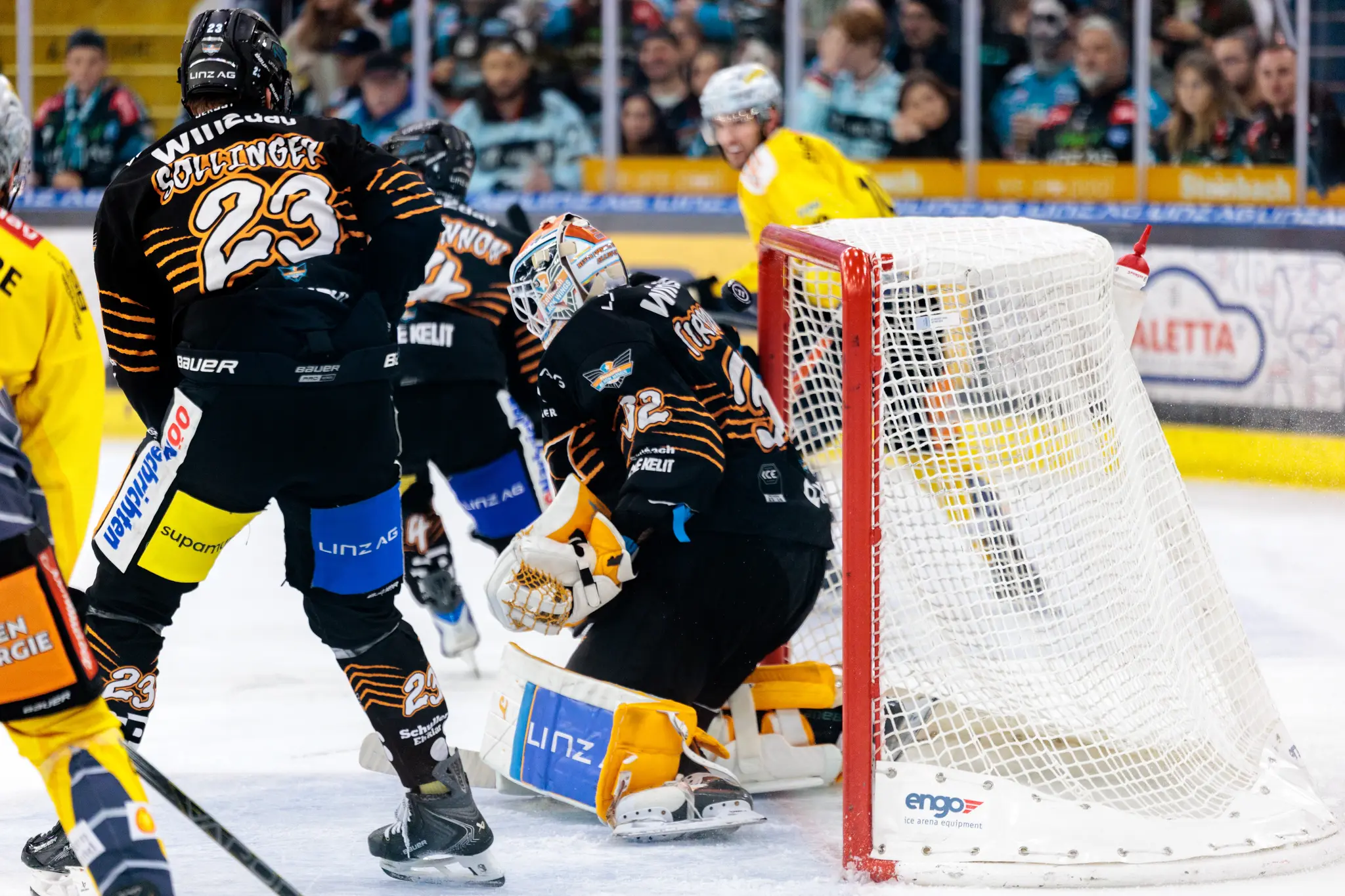 Der Torhüter der Black Wings Linz, Rasmus Tirronen, verteidigt in einer intensiven Spielszene sein Tor. Der Puck befindet sich zwischen Tirronen und Tor