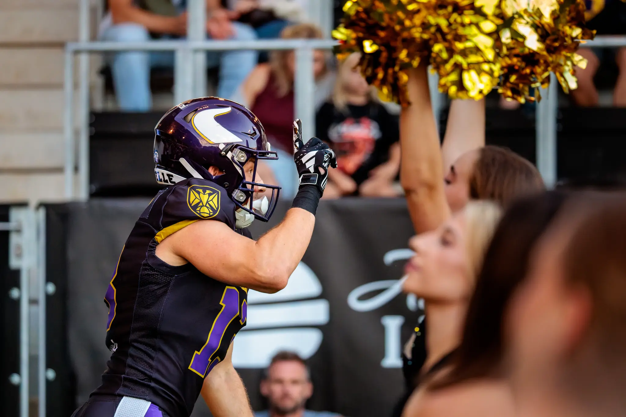 Touchdown-Jubel am Sideline: Philipp Haun (13) und Fabian Eder (11) feiern den Touchdown gemeinsam, im Hintergrund die Premium Dancers mit goldenen Pompoms.