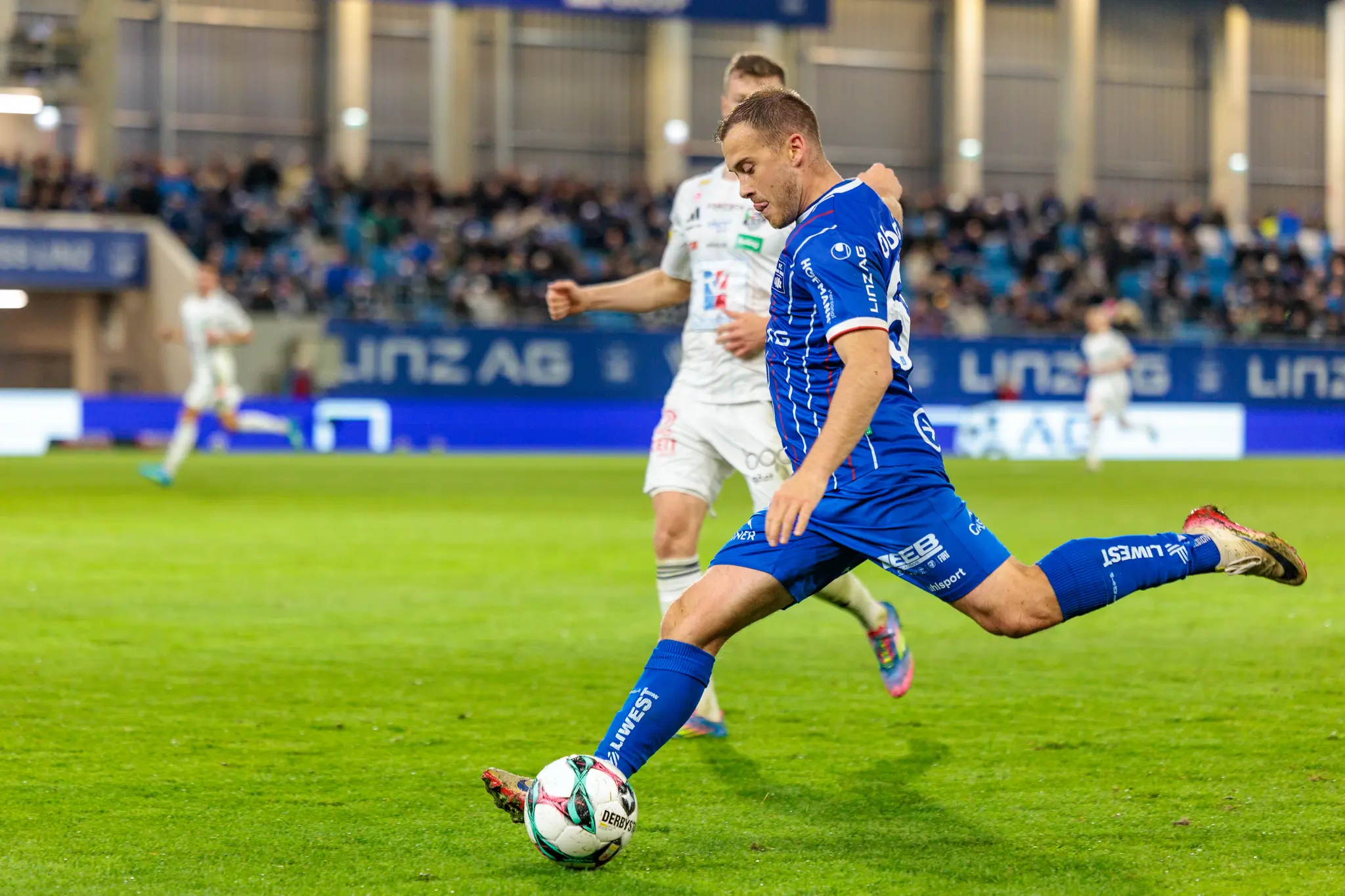 Ein Spieler des FC Blau-Weiß Linz führt einen kraftvollen Flanke aus