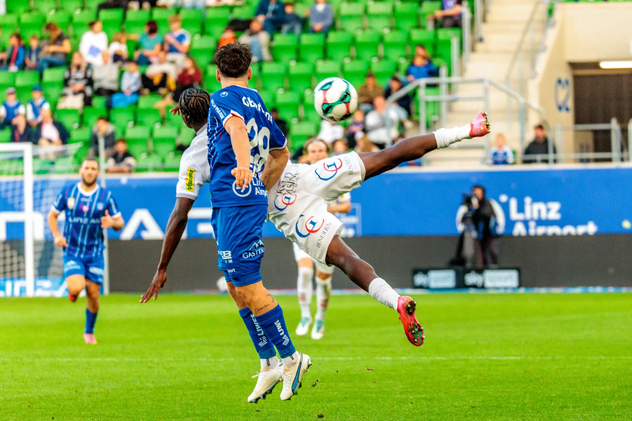 Der Stürmer des SCR Altach, Srdjan Hrstic, versucht mit einem akrobatischen Tritt in der Luft den Ball vor einem Gegenspieler von Blau-Weiß Linz zu erreichen