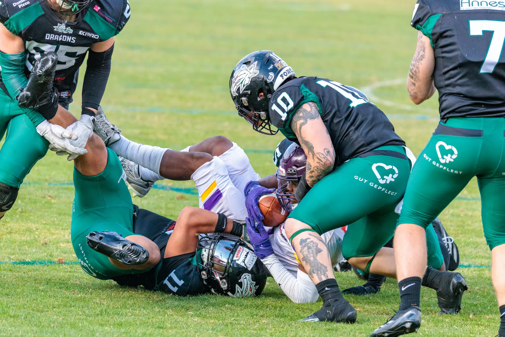 Harter Tackle im Feldmittelpunkt – Vikings-Spieler wird von mehreren Dragons-Spielern in schwarz-grünen Trikots gestoppt beim AFL-Playoff 2026