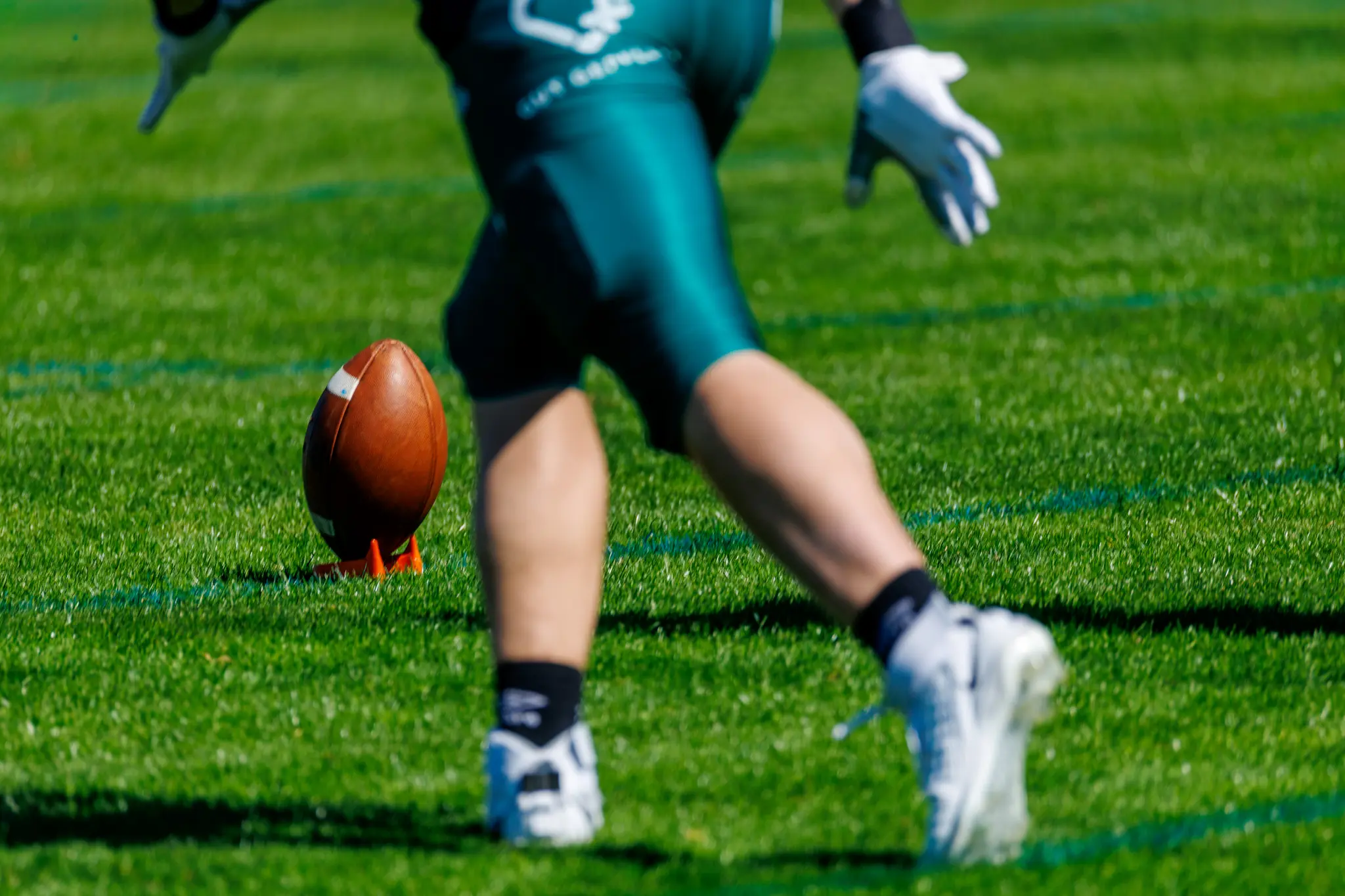 Ein American-Football-Spieler der Danube Dragons läuft für einen Kickoff an, während der Ball auf einem orangefarbenen Tee bereitsteht