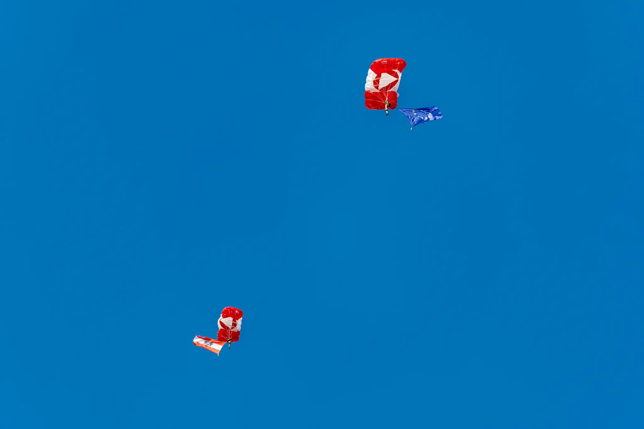 Zwei Fallschirmspringer schweben mit österreichischer und europäischer Flagge über dem Wiener Sport-Club-Stadion.