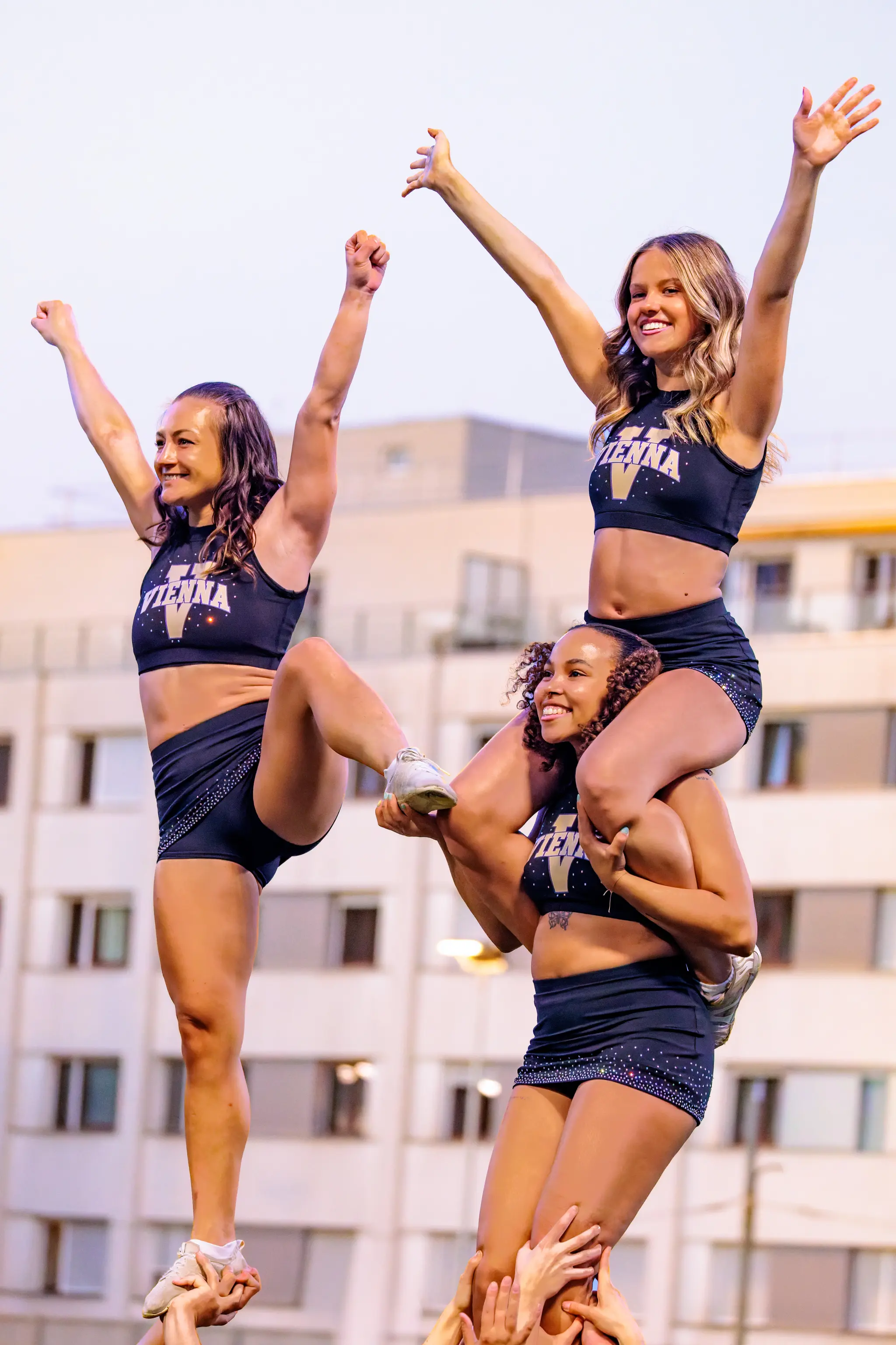 Luftakrobatik am Spielfeldrand: Zwei Flyer der Vienna Vikings Spirit Squad steigen hoch hinauf, die Fäuste zum Sieg gereckt, während die Basen unten sicher halten.