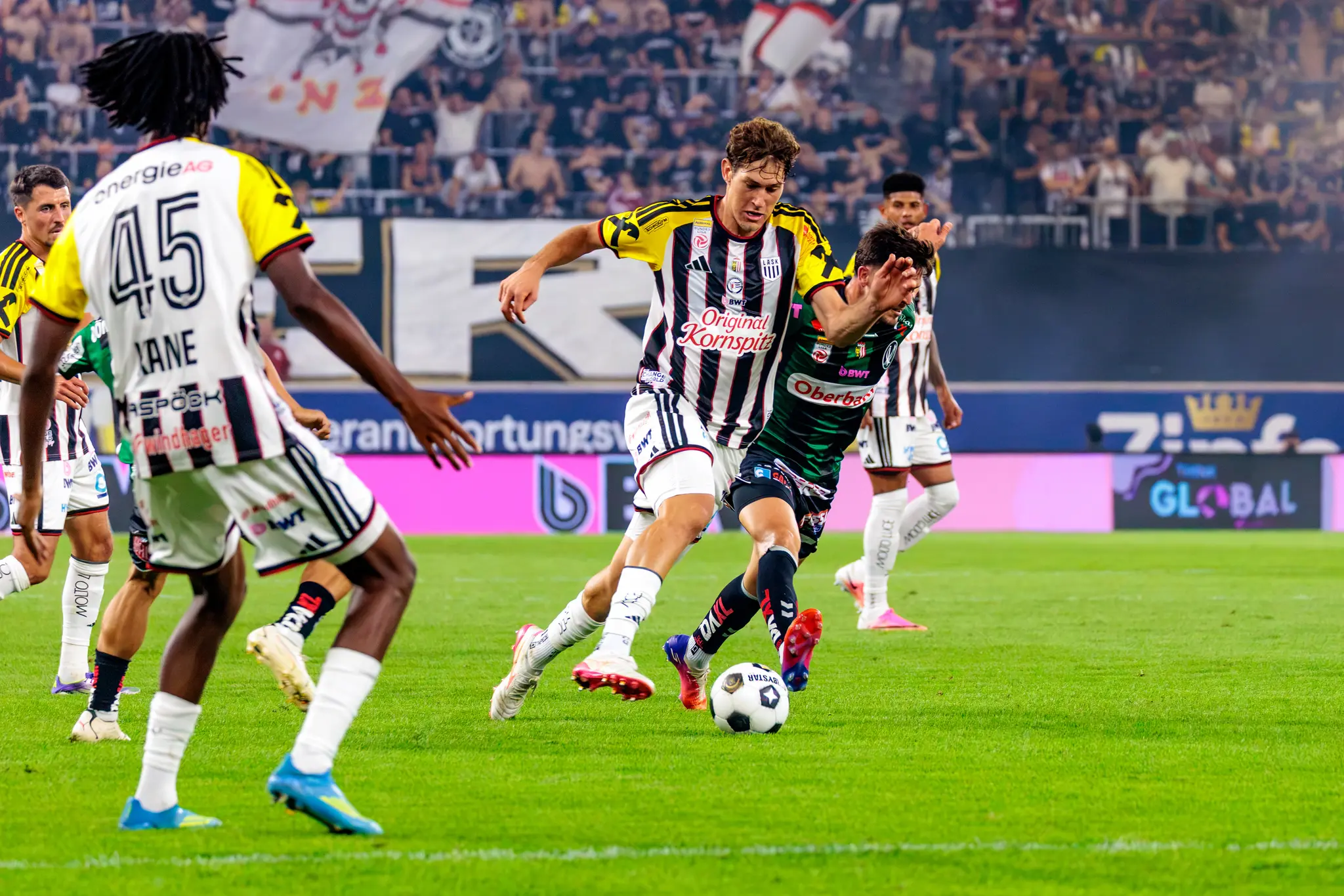Kane (Nr. 45) im Vordergrund, im Hintergrund ein Zweikampf zwischen LASK- und Ried-Spieler
