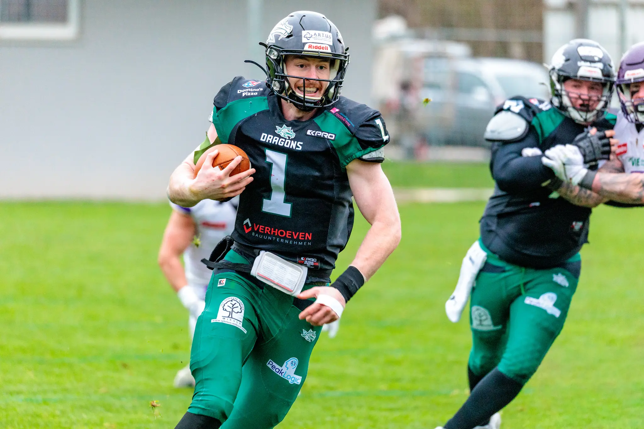 Ein American-Football-Spieler der Danube Dragons in grüner Spielermontur rennt mit dem Ball nach vorne, während ein Teamkollege blockt