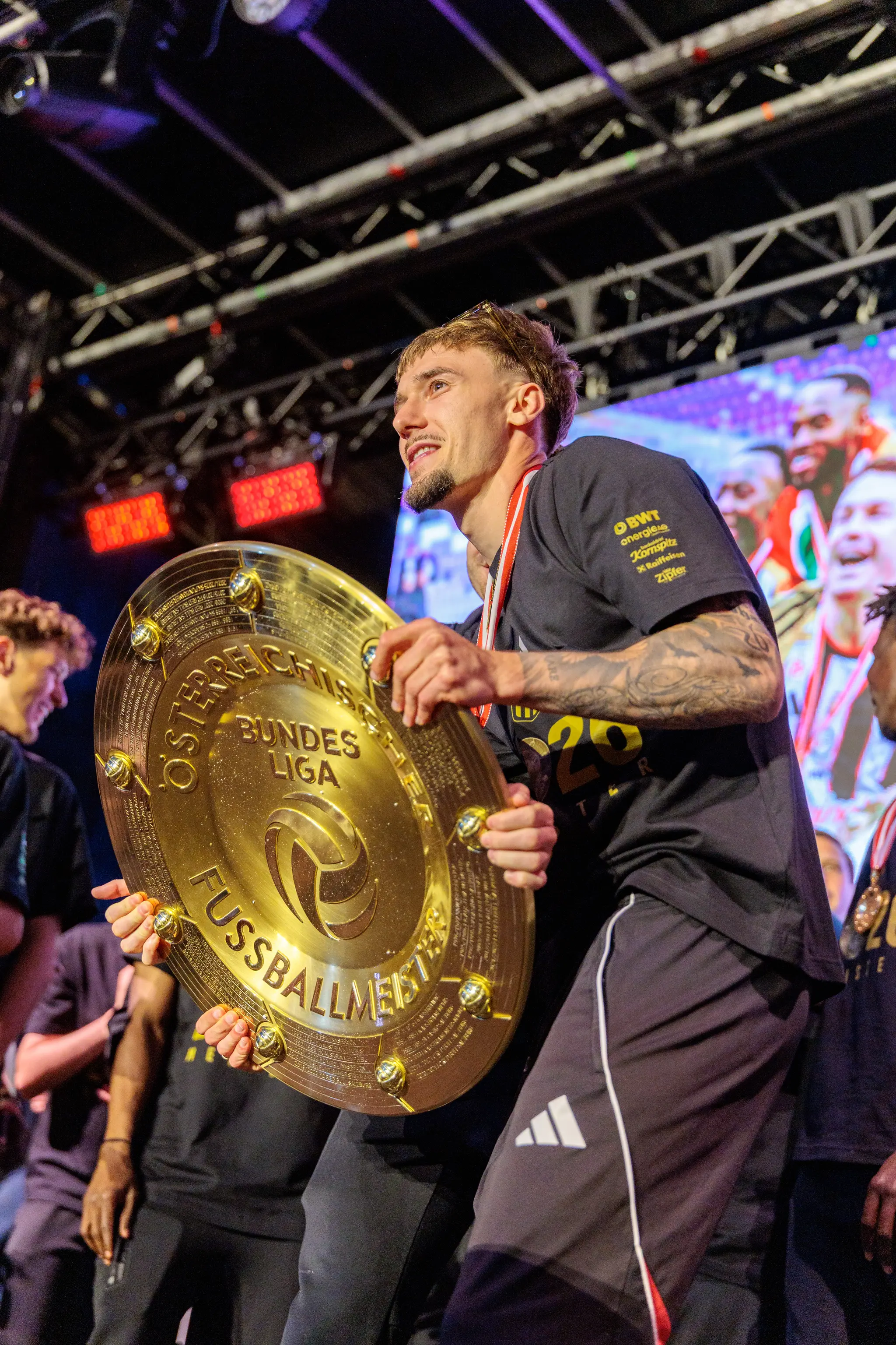 Ein LASK-Spieler präsentiert stolz den goldenen Meisterteller während der feierlichen Siegerehrung in Linz