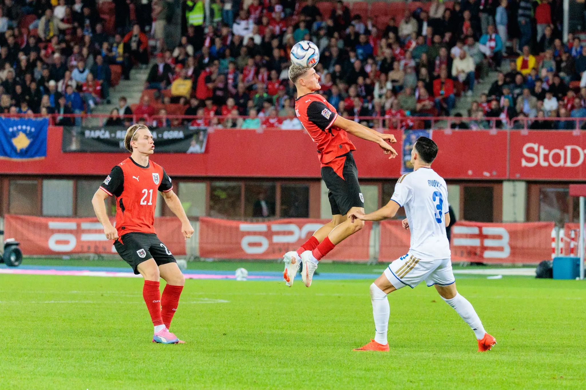 Ein Spieler Österreichs steigt hoch und köpft den Ball aus der Gefahrenzone, daneben läuft Patrick Wimmer (21).