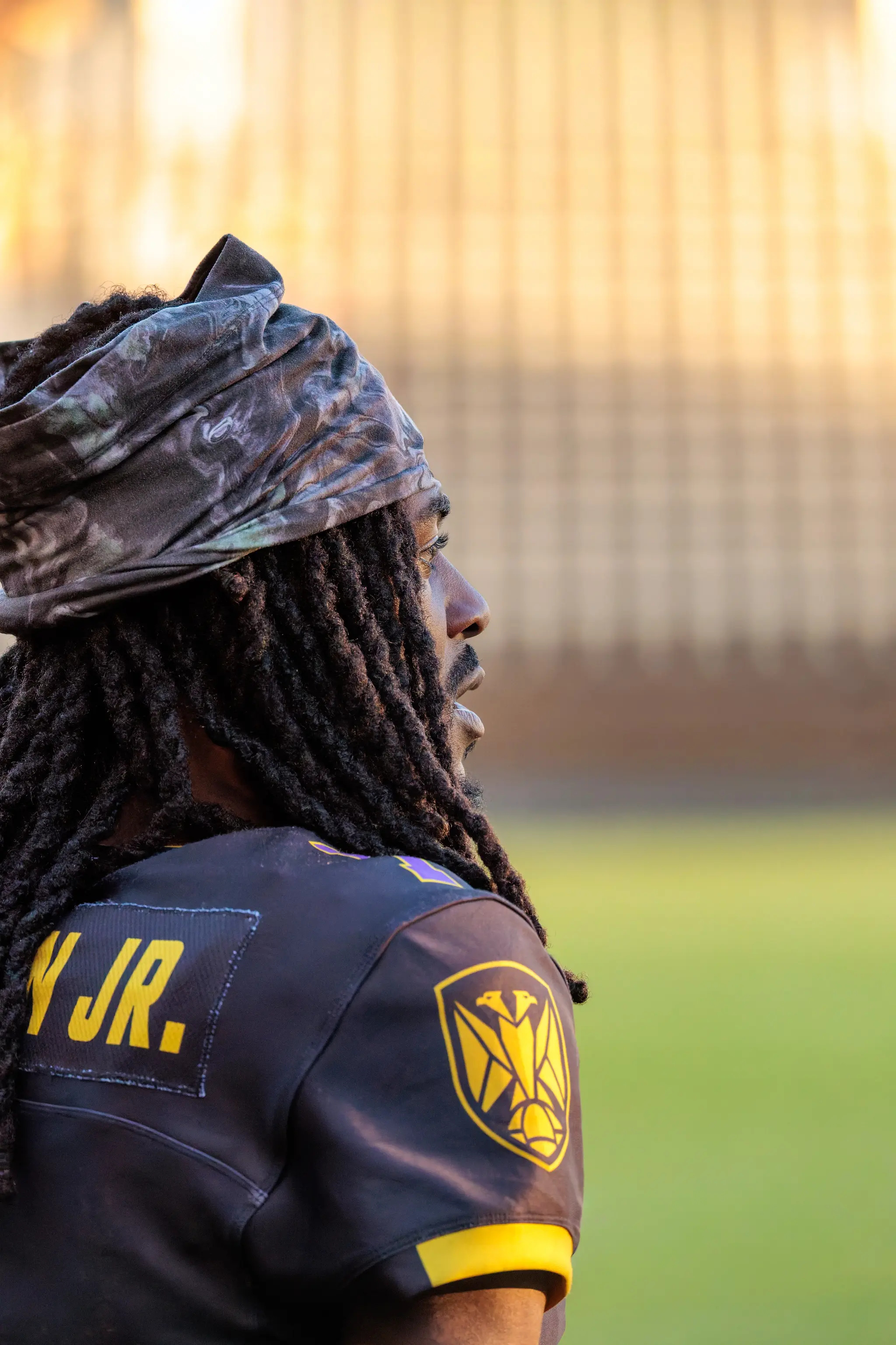 Fokus am Sideline: Darrell Stewart Jr (8) verfolgt das Geschehen konzentriert, die Dreadlocks unter dem Tuch, das Abendlicht im Rücken.