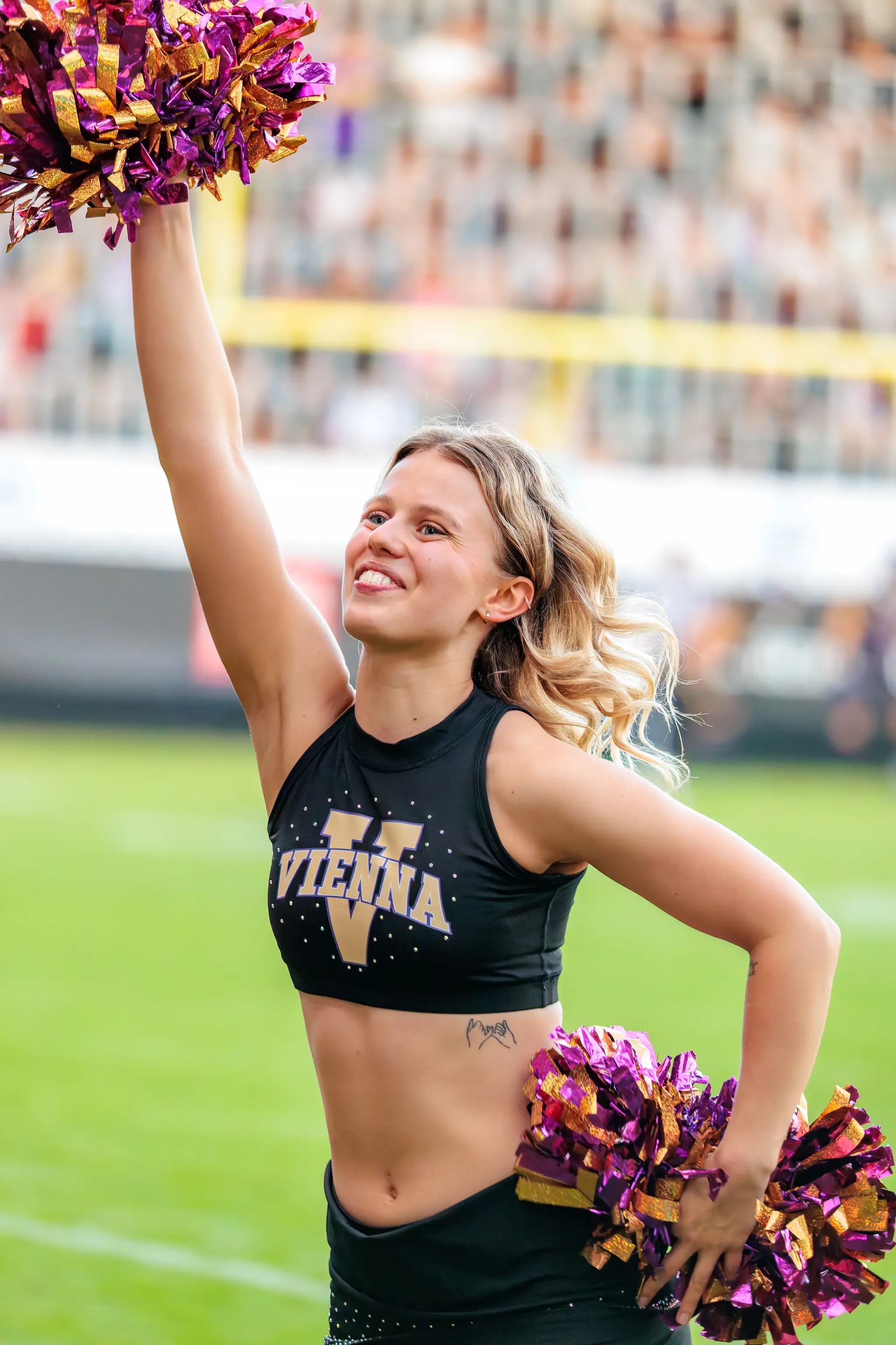 Mit erhobenem Pompon posiert eine Tänzerin des Vienna Vikings Cheer Squads lächelnd.