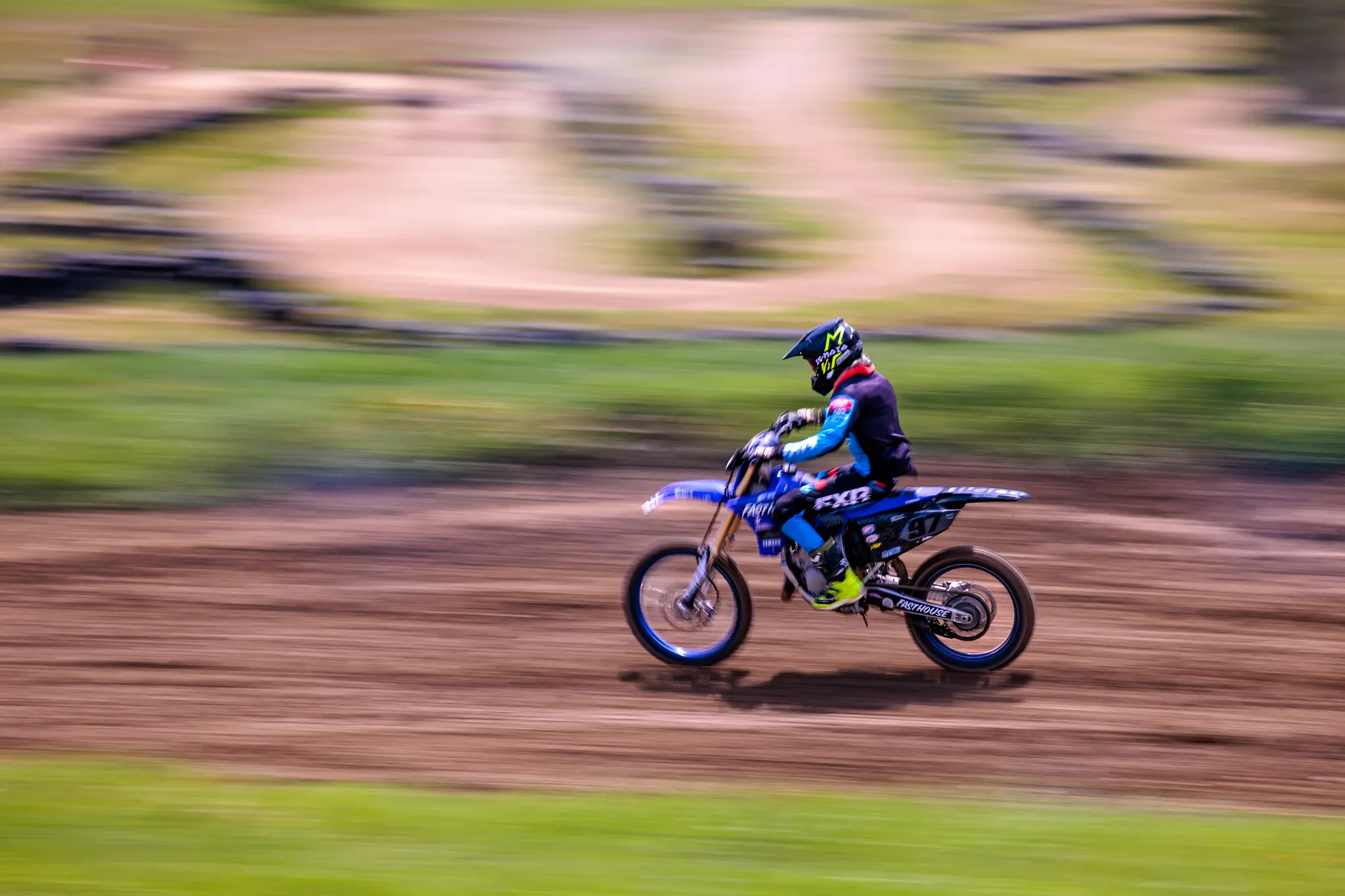 Motocross-Rennfahrer auf blauem Dirtbike in schneller Panning-Aufnahme