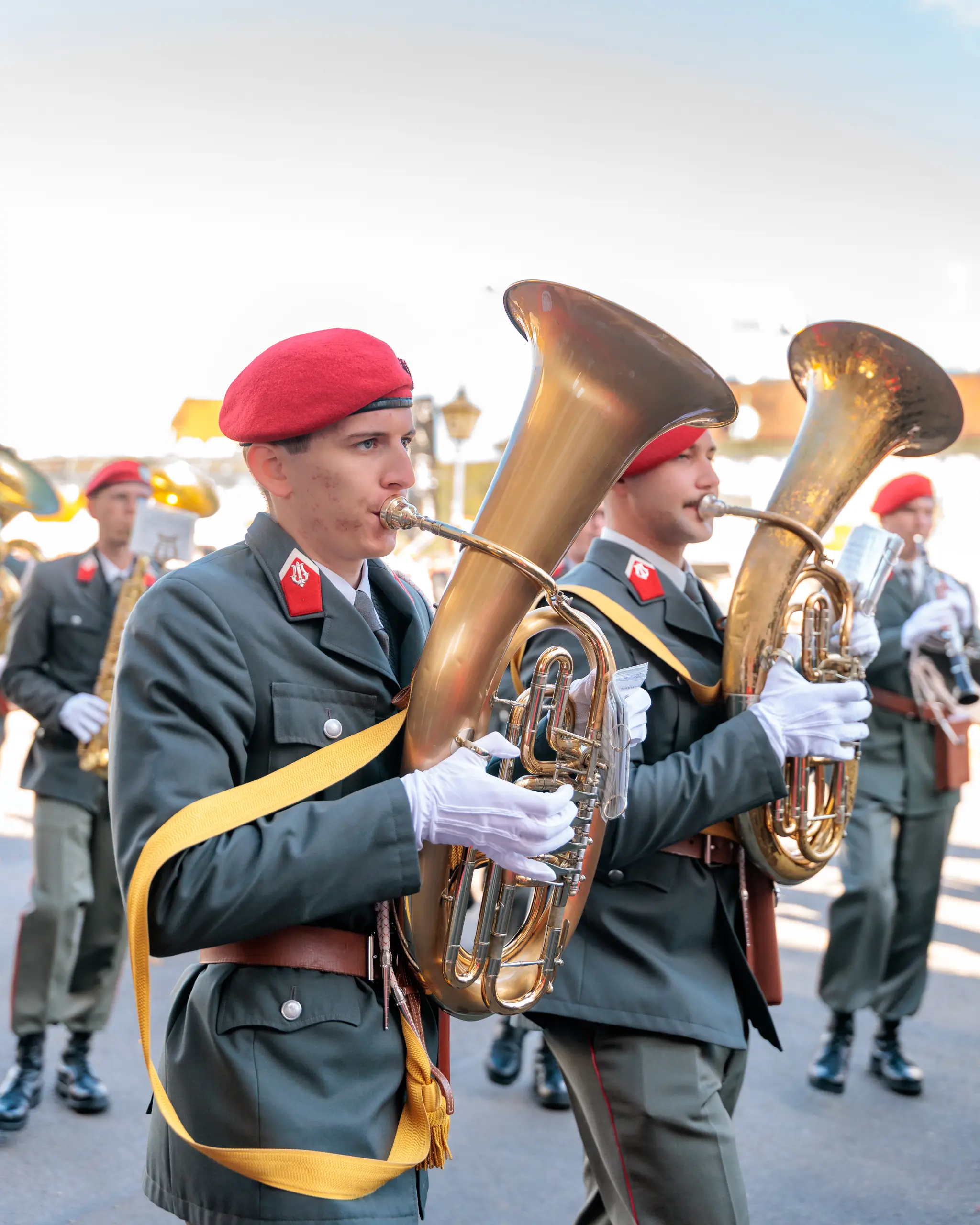 Zwei Militärmusiker mit roten Baretten spielen auf großen Tubas, hinter ihnen reihen sich weitere Musikerinnen und Musiker der Bundesheer-Kapelle ein.