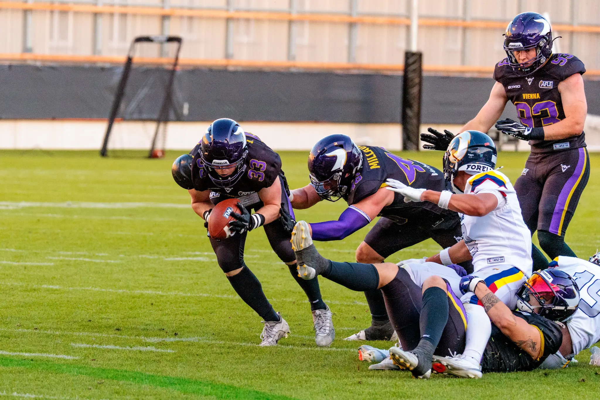 Ein Spieler der Vienna Vikings hält den Football während eines intensiven Tacklings gegen die Alpine Rams in der AFLE