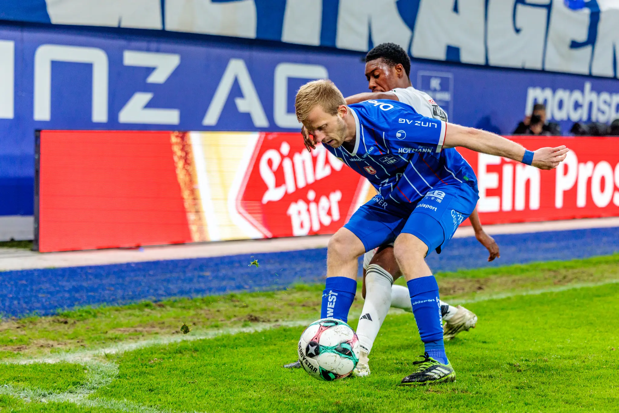 Ein Spieler von Blau-Weiß Linz schirmt den Ball effektiv gegen einen Gegenspieler des Wolfsberger AC ab