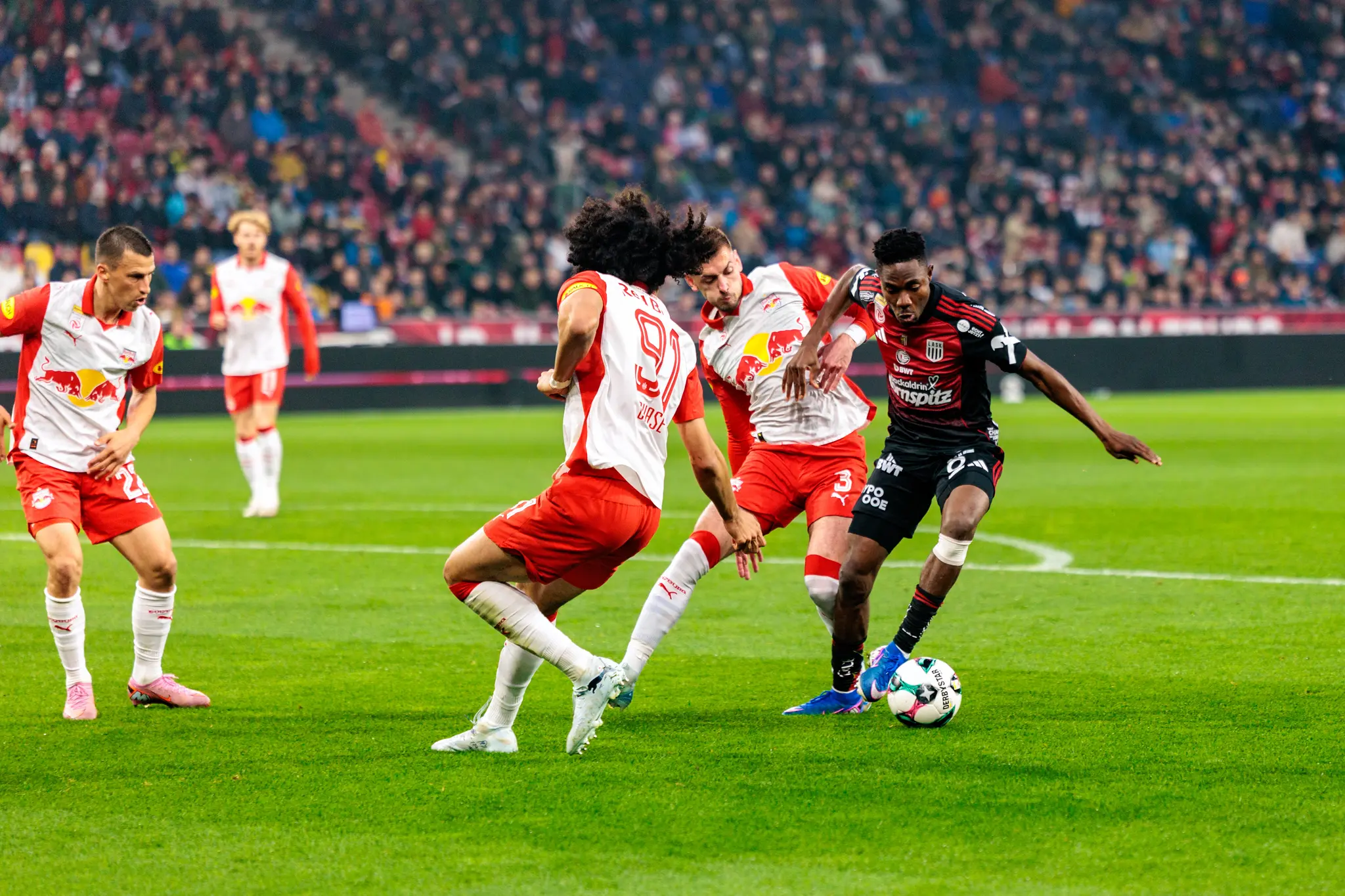 Ein Spieler des LASK setzt sich in der ADMIRAL Bundesliga durch ein geschicktes Dribbling gegen mehrere Gegenspieler von Red Bull Salzburg durch