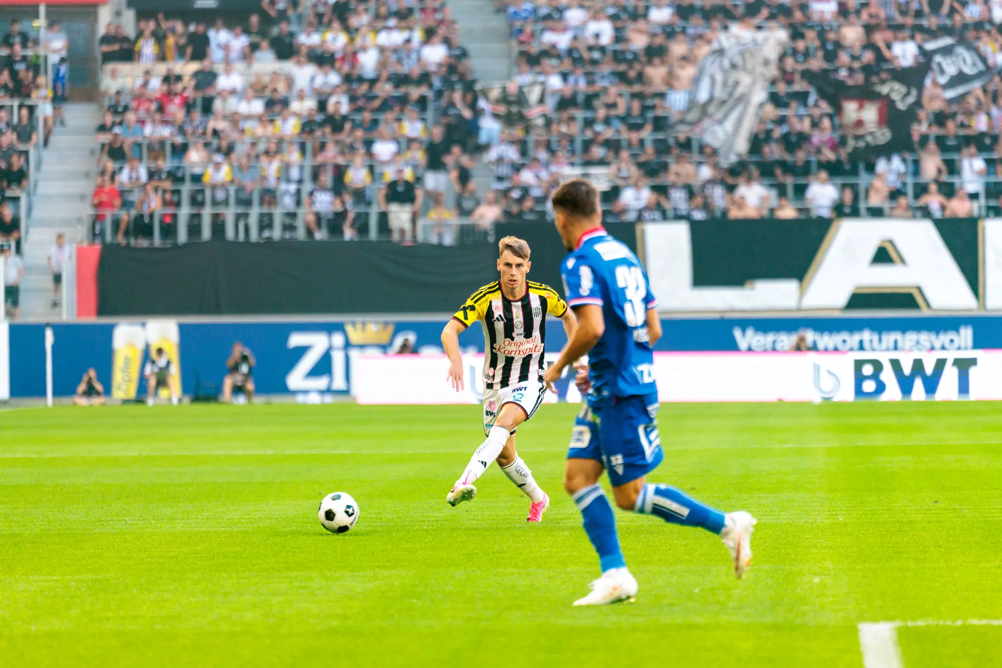 LASK-Angreifer dribbelt mit dem Ball am Fuße gegen einen GAK-Verteidiger und sucht den Weg zum Tor