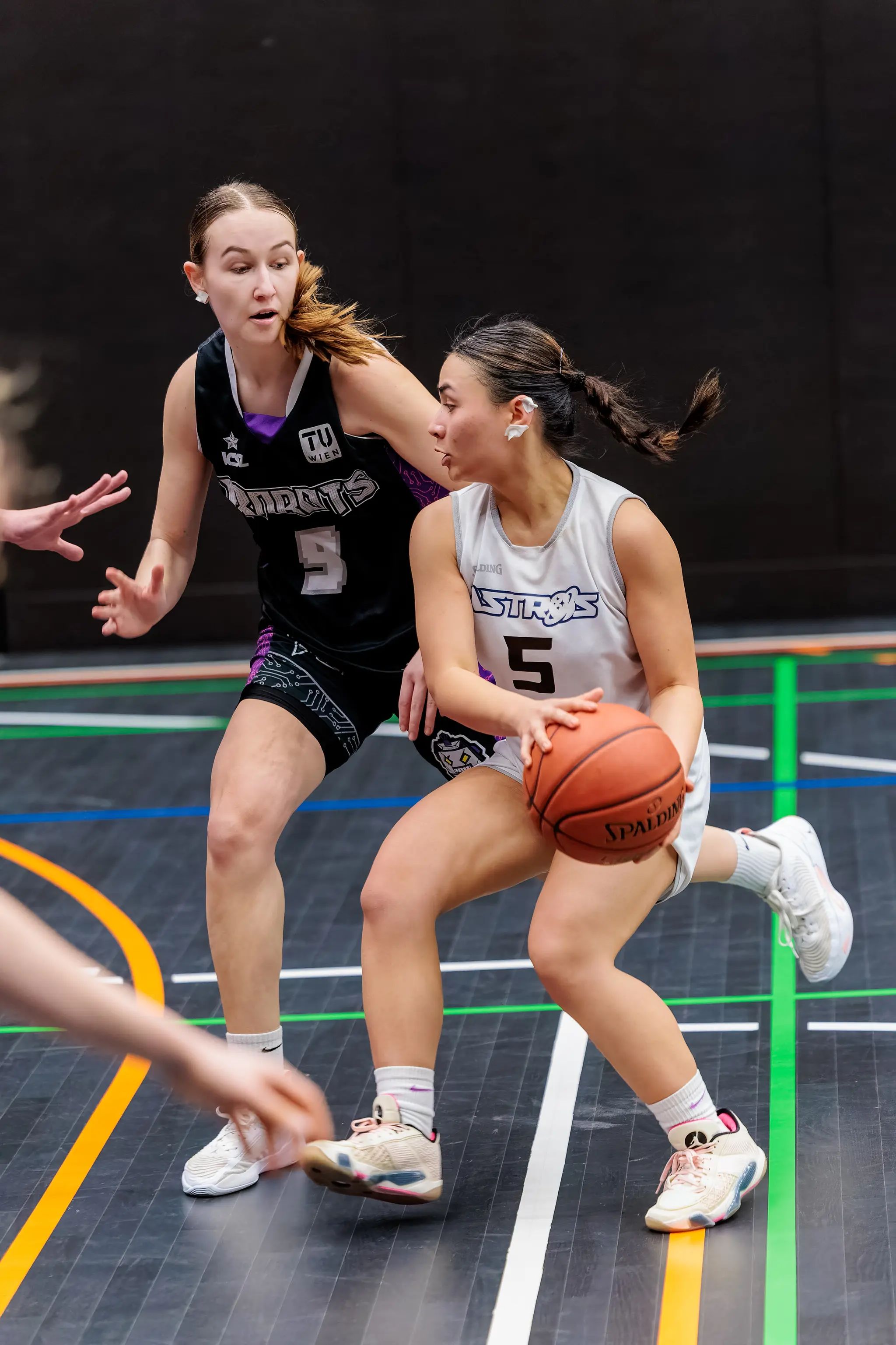 Eine Basketballspielerin im weißen Trikot dribbelt den Ball, während eine Gegnerin im schwarzen Trikot sie während eines ACSL Halbfinalspiels verteidigt