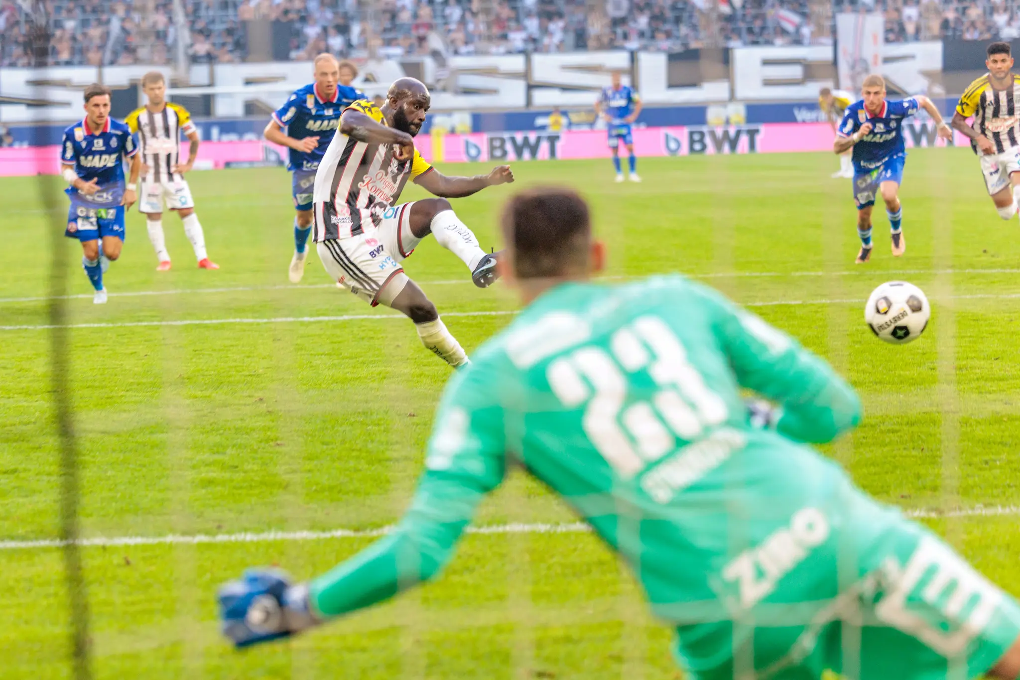 Adeniran schießt den Elfmeter auf das Tor, während der GAK-Torhüter Stankovic in die richtige Ecke springt