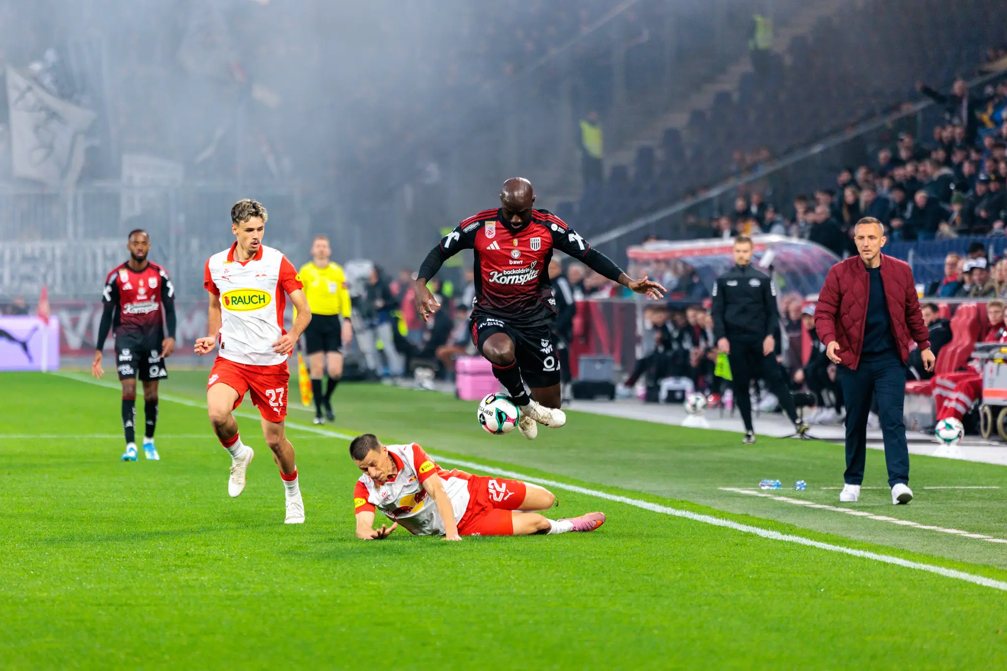 Ein Spieler des LASK setzt in der ADMIRAL Bundesliga zu einem spektakulären Sprung über einen am Boden liegenden Kontrahenten von Red Bull Salzburg an