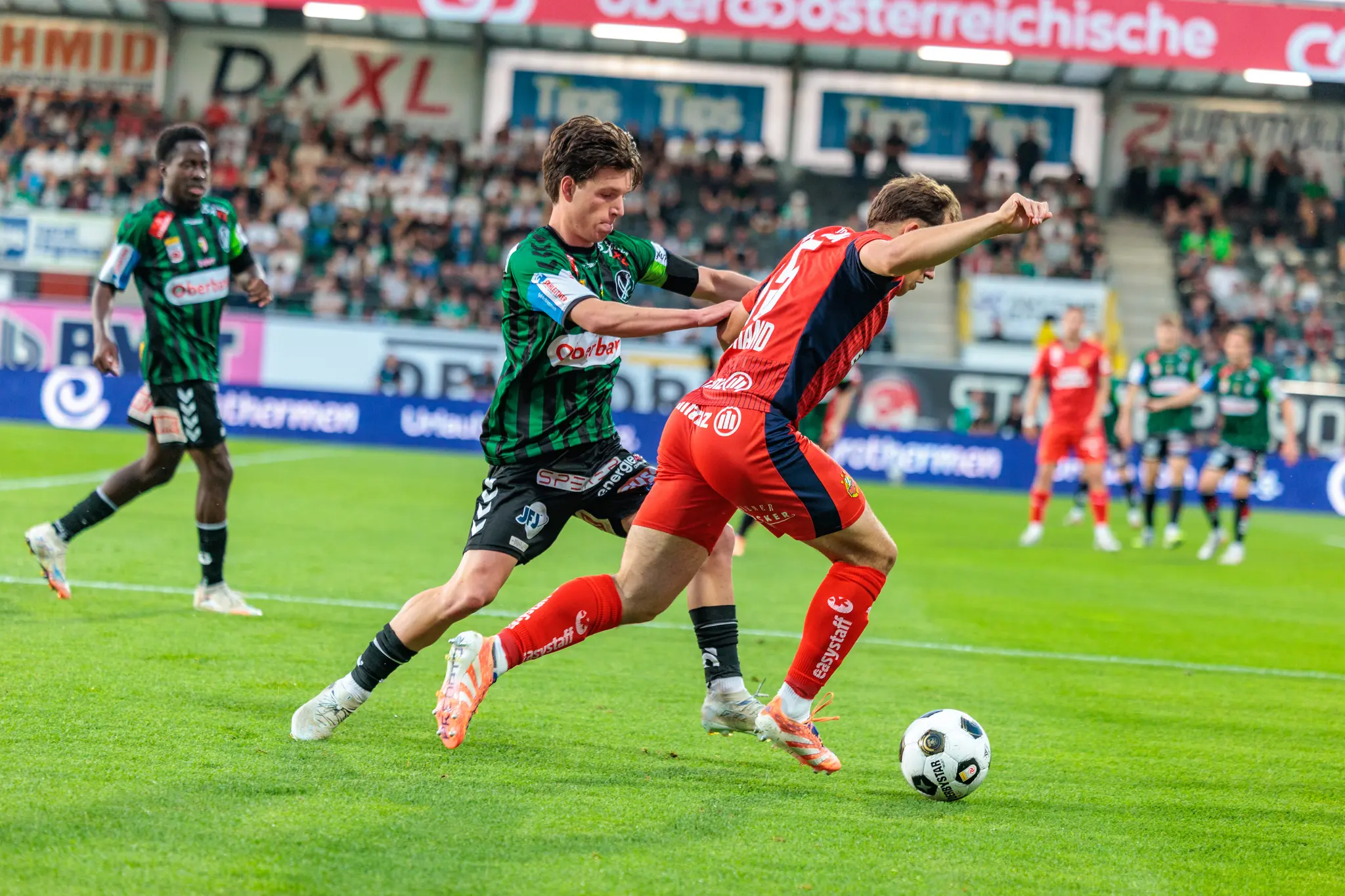 Ein Spieler von Rapid Wien behauptet den Ball in einem intensiven Laufduell während des Bundesliga-Playoff-Spiels gegen SV Ried