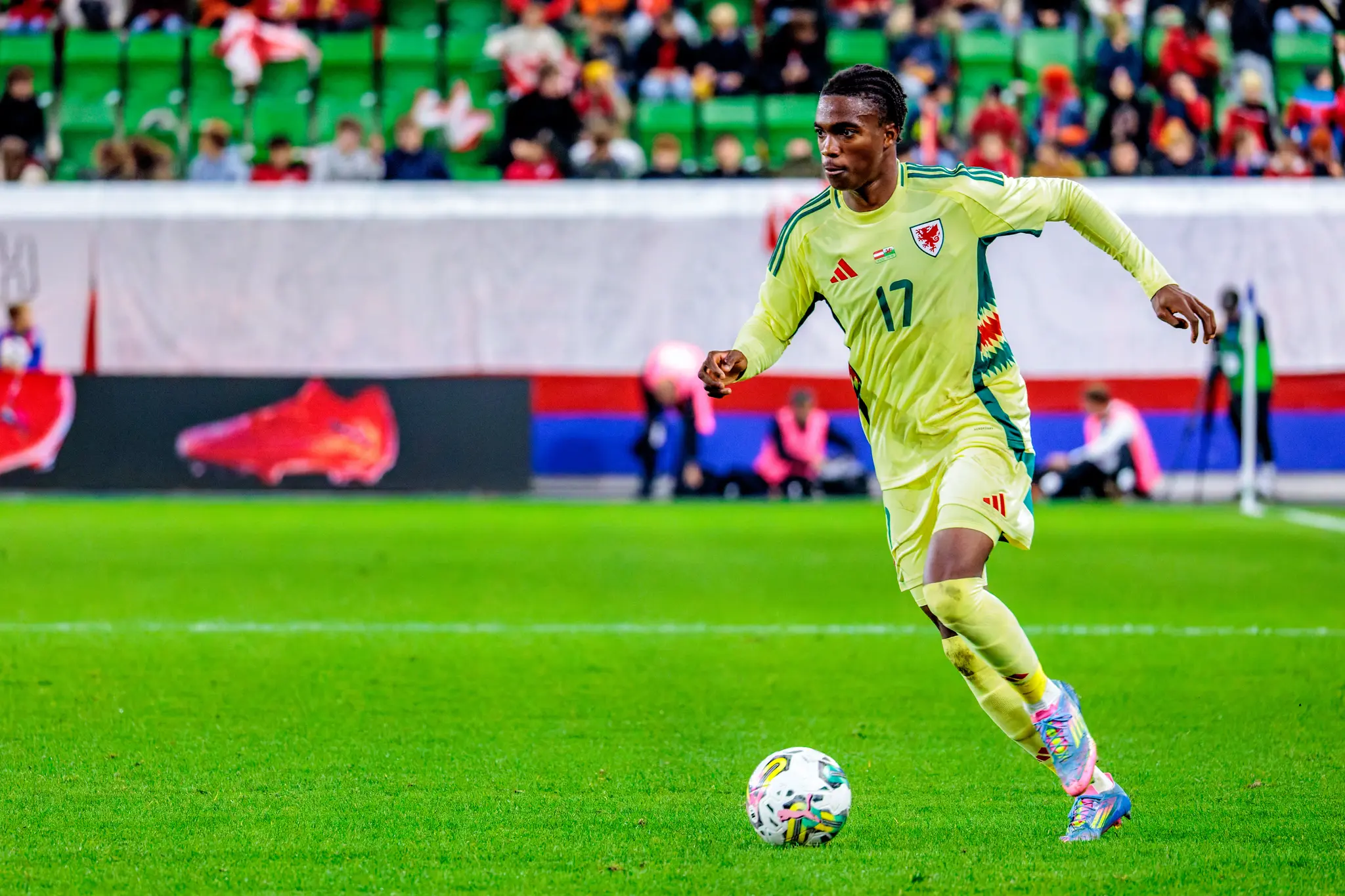 Der walisische U21-Nationalspieler Tanatswa Nyakuhwa dribbelt in seinem gelben Trikot mit der Nummer 17 konzentriert mit dem Ball