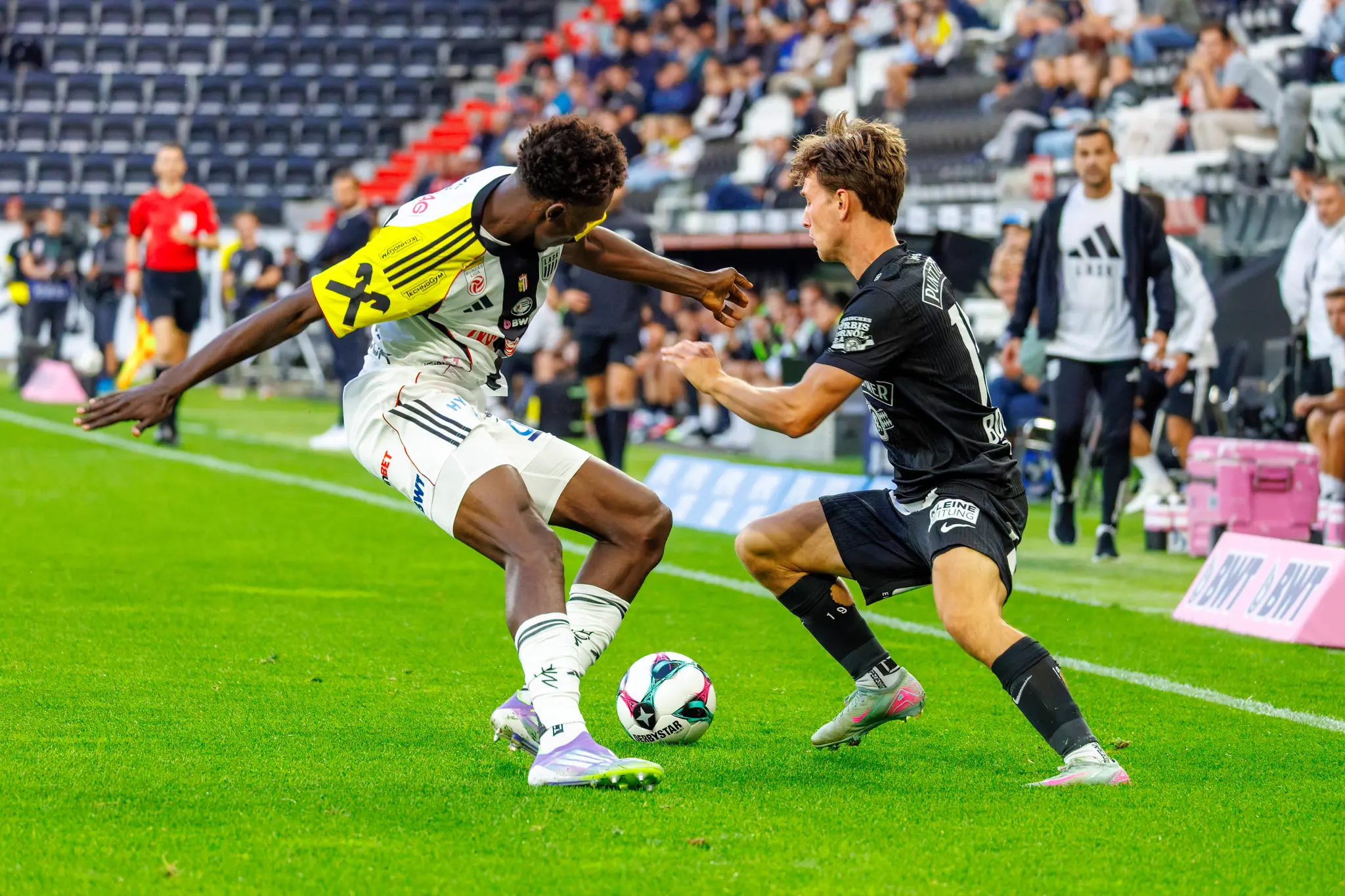 Intensiver Zweikampf um den Ball zwischen einem Spieler des LASK im hellen Trikot und seinem Gegenspieler im dunklen Dress während eines Fußballspiels