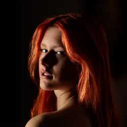 Dramatisches Porträt einer jungen Frau mit leuchtend roten Haaren, die mit intensivem Blick über die Schulter schaut